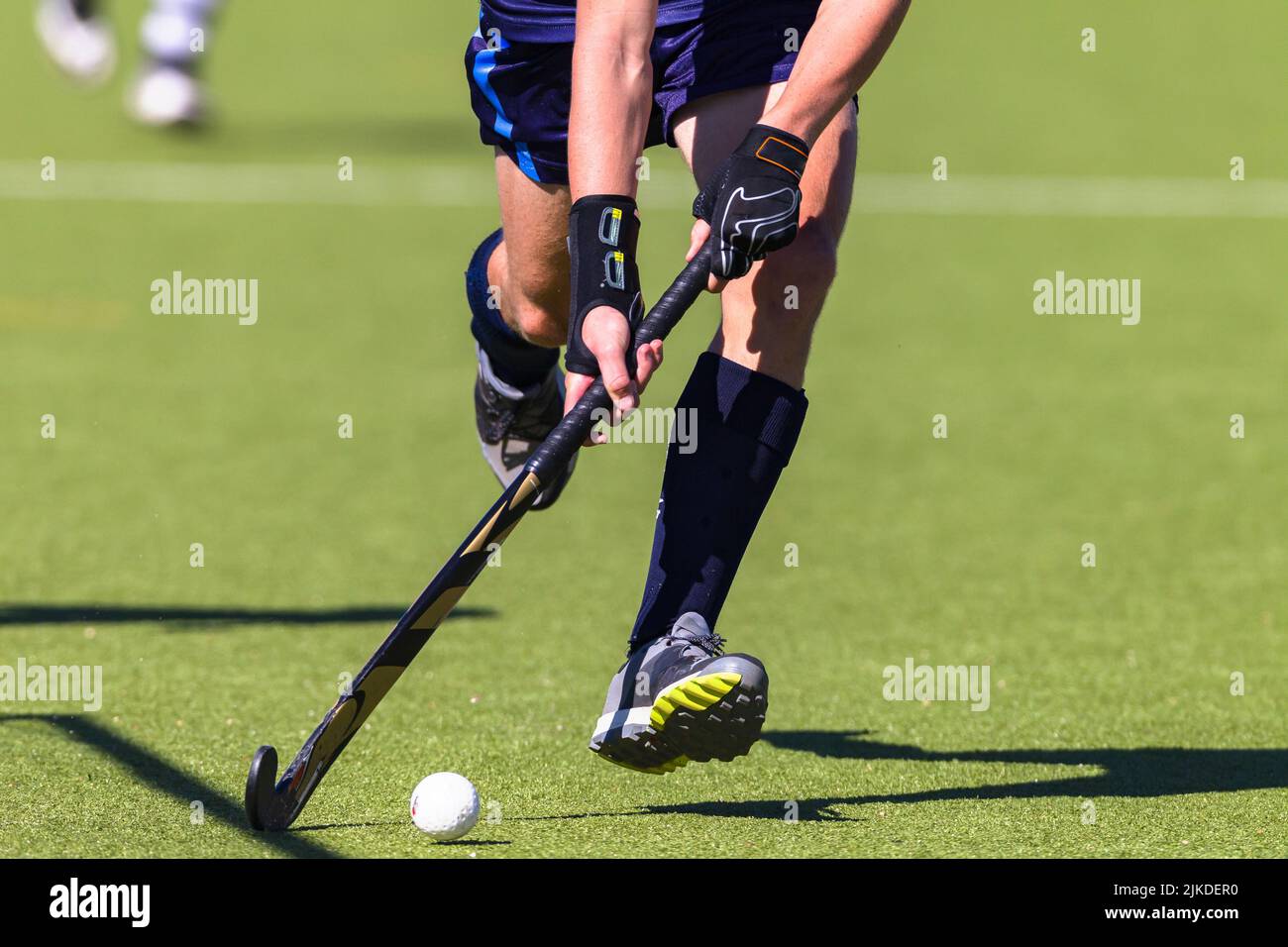 Hockey game player half body hands legs running with ball and stick on