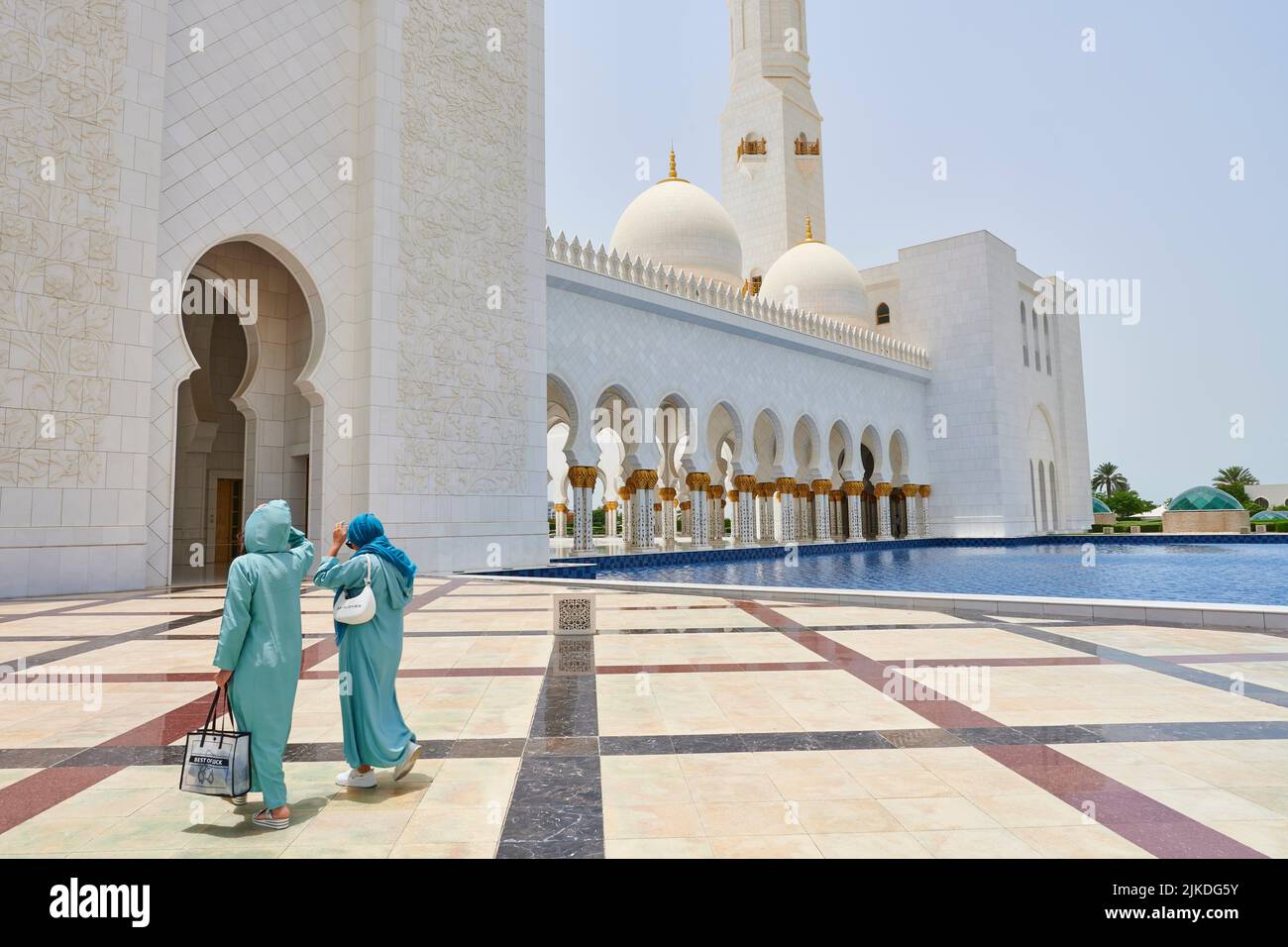 Two female visitors wearing over-garment entering the Sheikh Zayed Mosque. Abu Dhabi. United Arab Emirates. Stock Photo