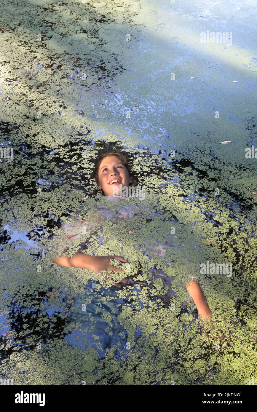 Photo montage of a girl semi immersed in water of a small pond covered with water lenses, Eure-et-Loir department, Centre-Val-de-Loire region, Stock Photo