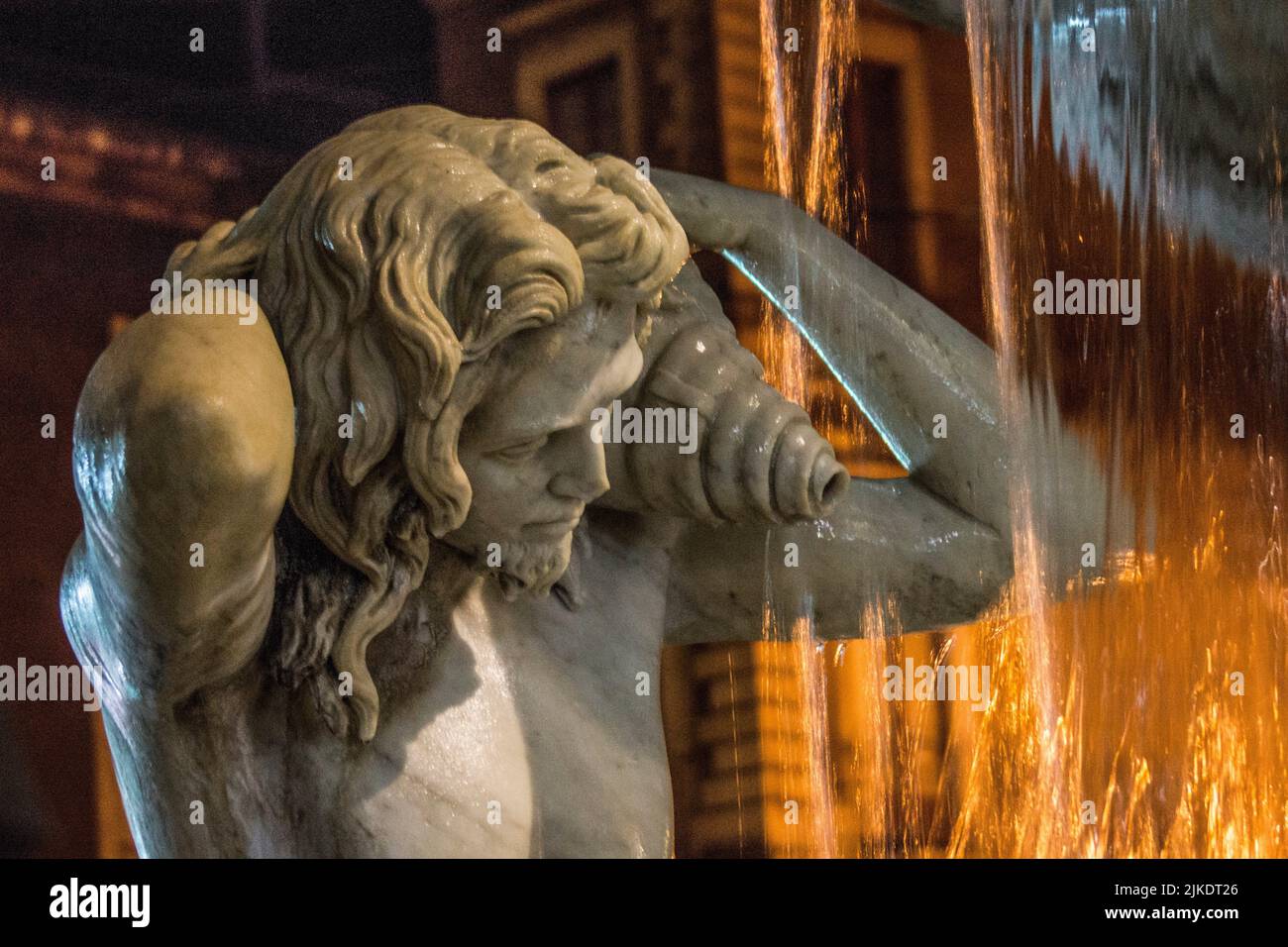 Detail, one of two fountain tritons. Amenano Fountain, night view. Piazza Duomo, Metropolitan City of Catania, Sicily, Italy. Stock Photo