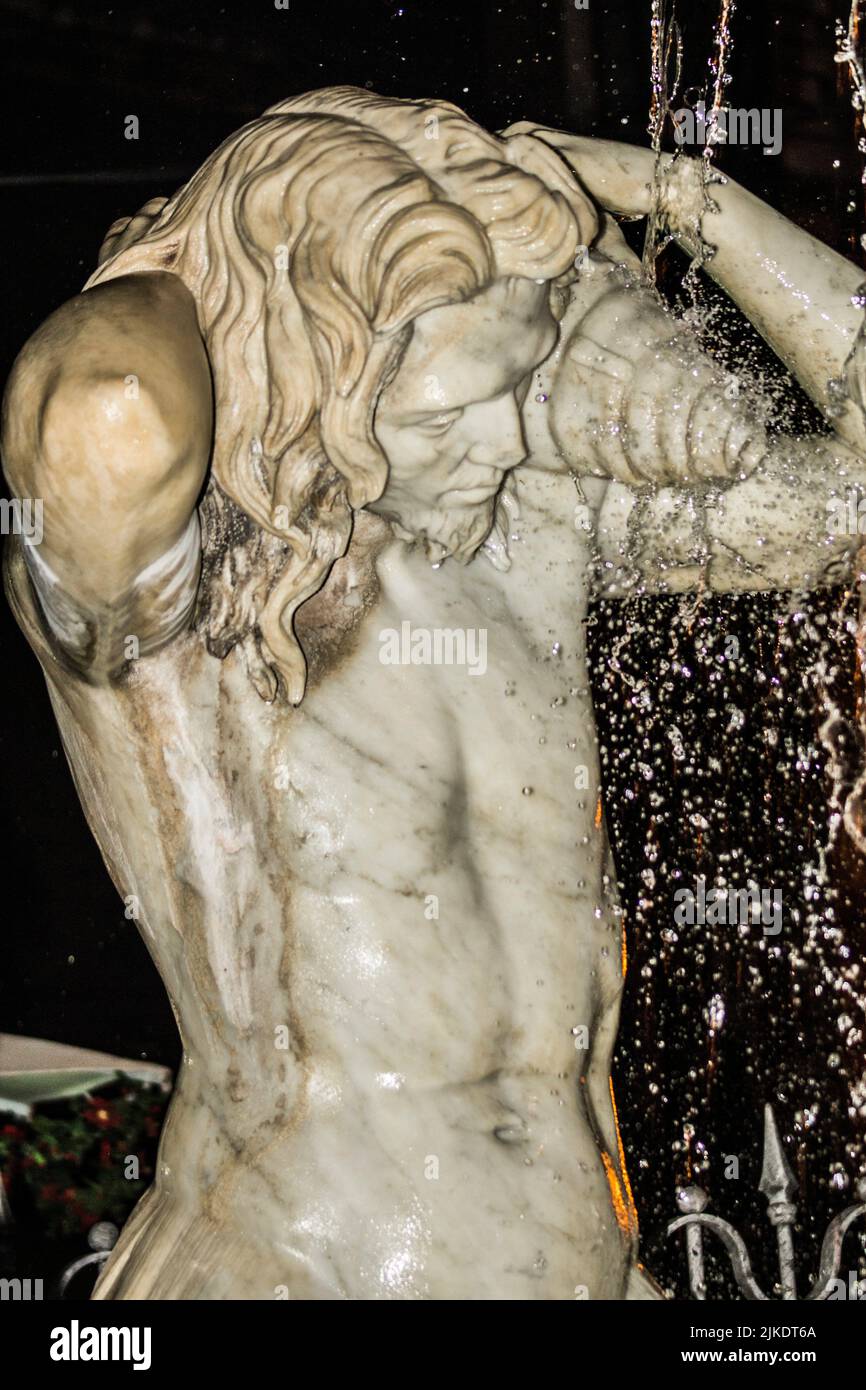 Detail, one of two fountain tritons. Amenano Fountain, night view. Piazza Duomo, Metropolitan City of Catania, Sicily, Italy. Stock Photo