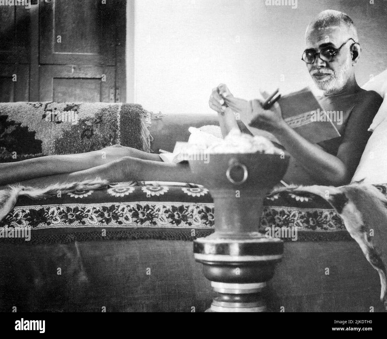 Black and white photograph portrait of Indian sage Sri Ramana Maharshi reading a book while lying on a couch, Tiruvannamalai, India Stock Photo