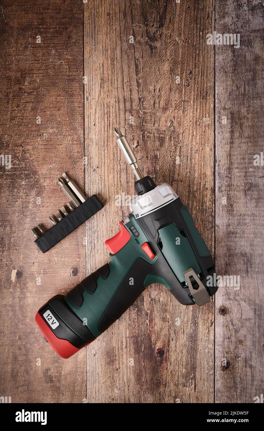 Cordless screwdriver drill and bit set lie on wooden table