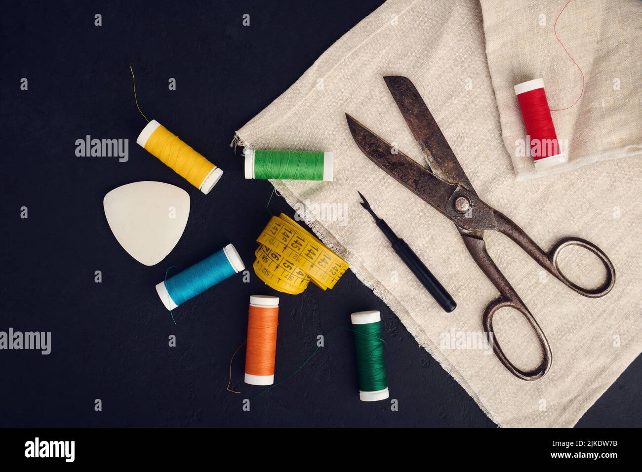 Old scissors, spools of colored thread, centimeter and tailors chalk, flat lay, concept of sewing clothes Stock Photo