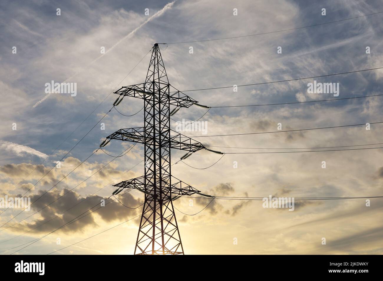 Silhouette of high voltage tower with electrical wires on background of sunset sky and clouds. Electricity transmission lines, power supply concept Stock Photo