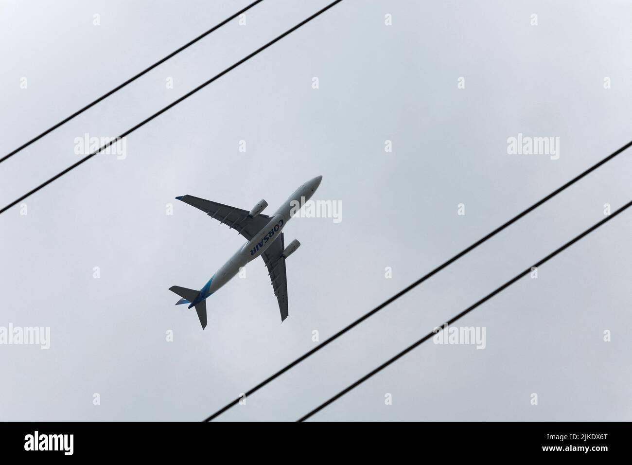 An Airbus A330 operated by Corsair flies over electric lines in Villebon-sur-Yvette, near Paris, France, August 1, 2022. REUTERS/Benoit Tessier Stock Photo