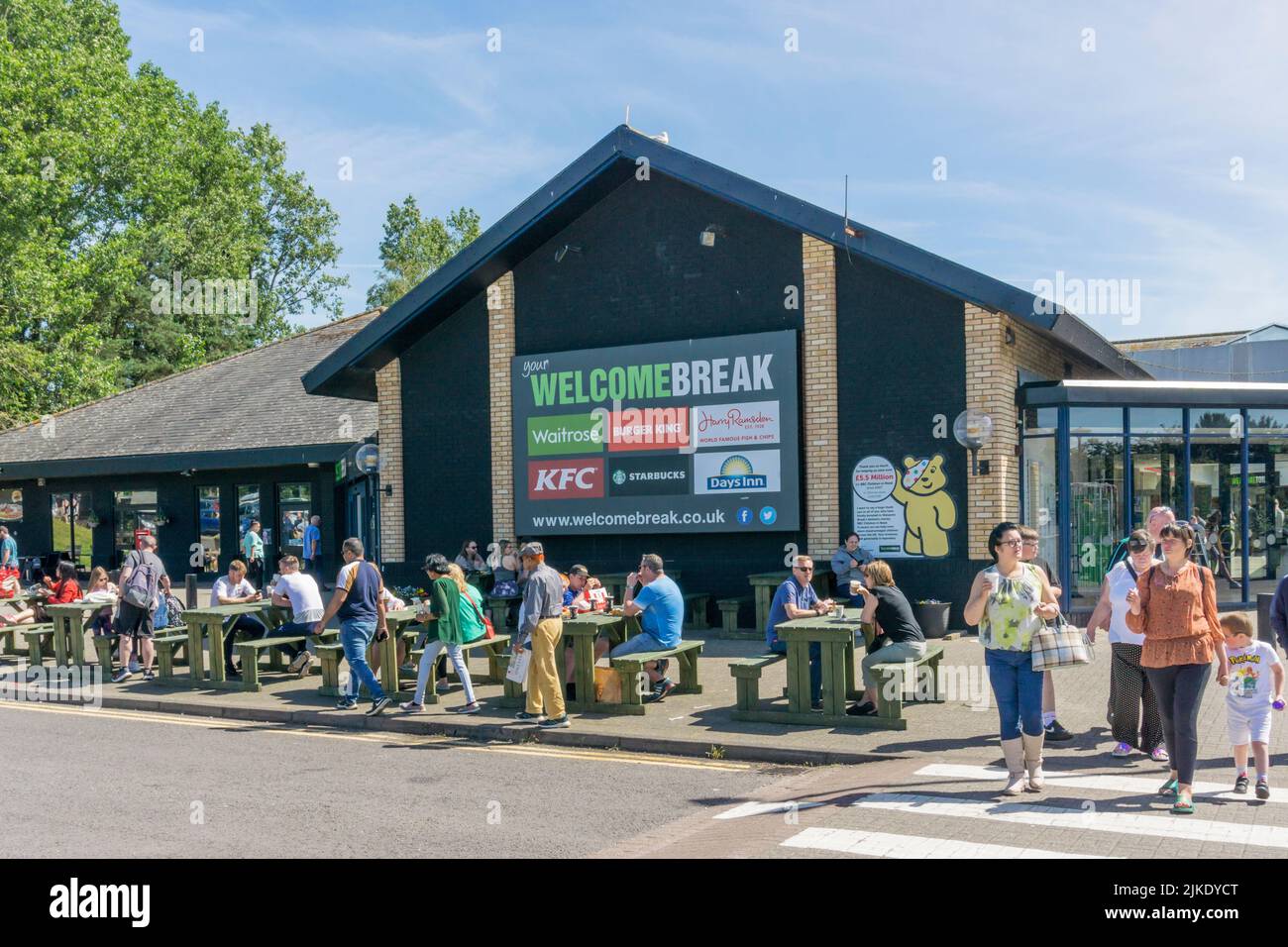 People eating & drinking in the sun outside Gretna Green WelcomeBreak motorway services on the A74M. Stock Photo