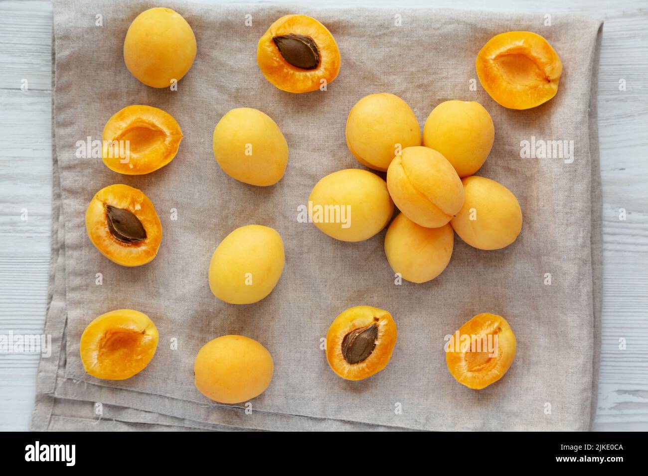 Raw White Apricot Angelcots on a white wooden surface, top view. Flat lay, overhead, from above. Stock Photo