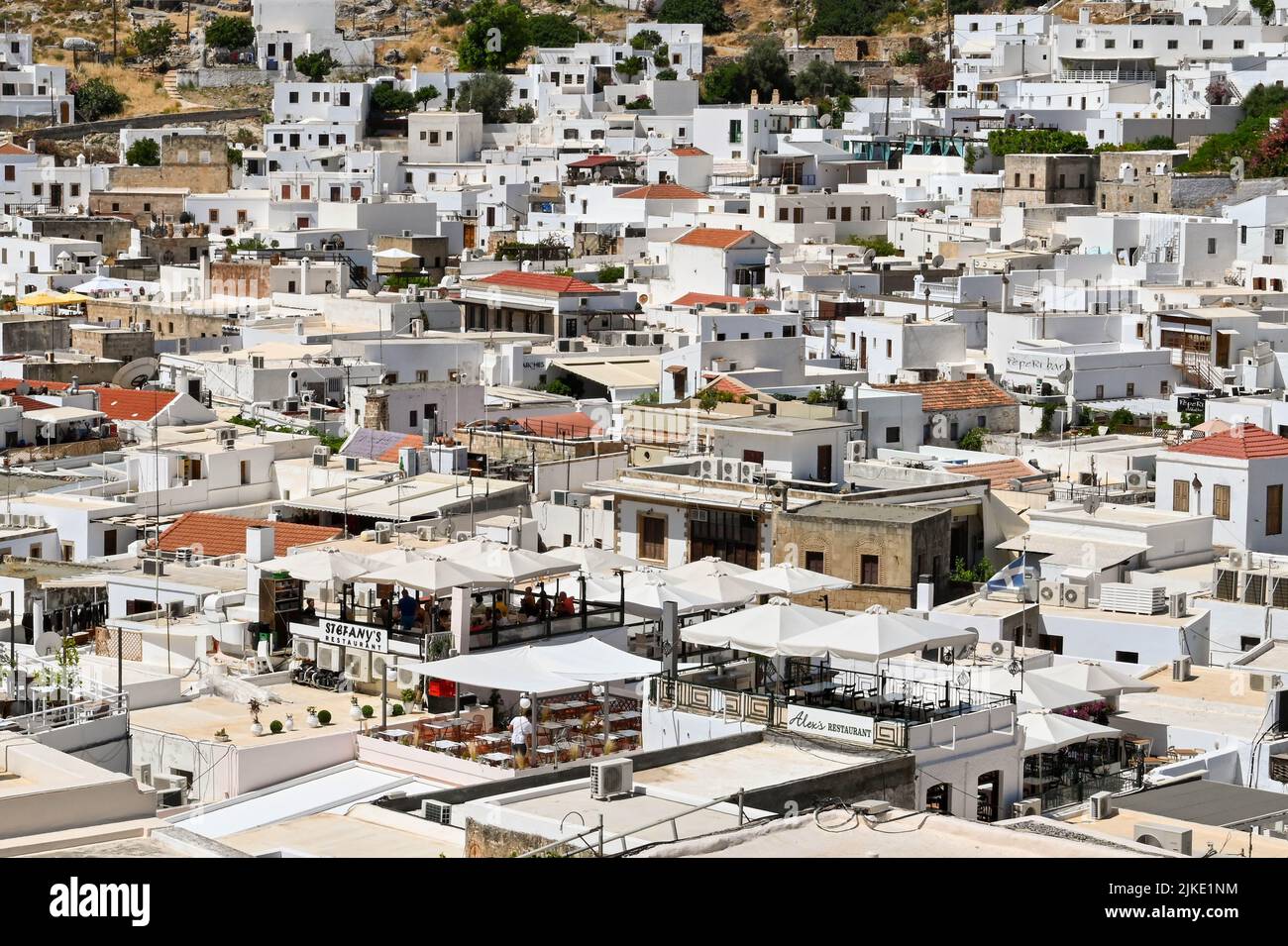 Lindos, Rodes, Greece - May 2022: Aerial view of restaurants and other whitewashed buildings in the town of Lindos Stock Photo