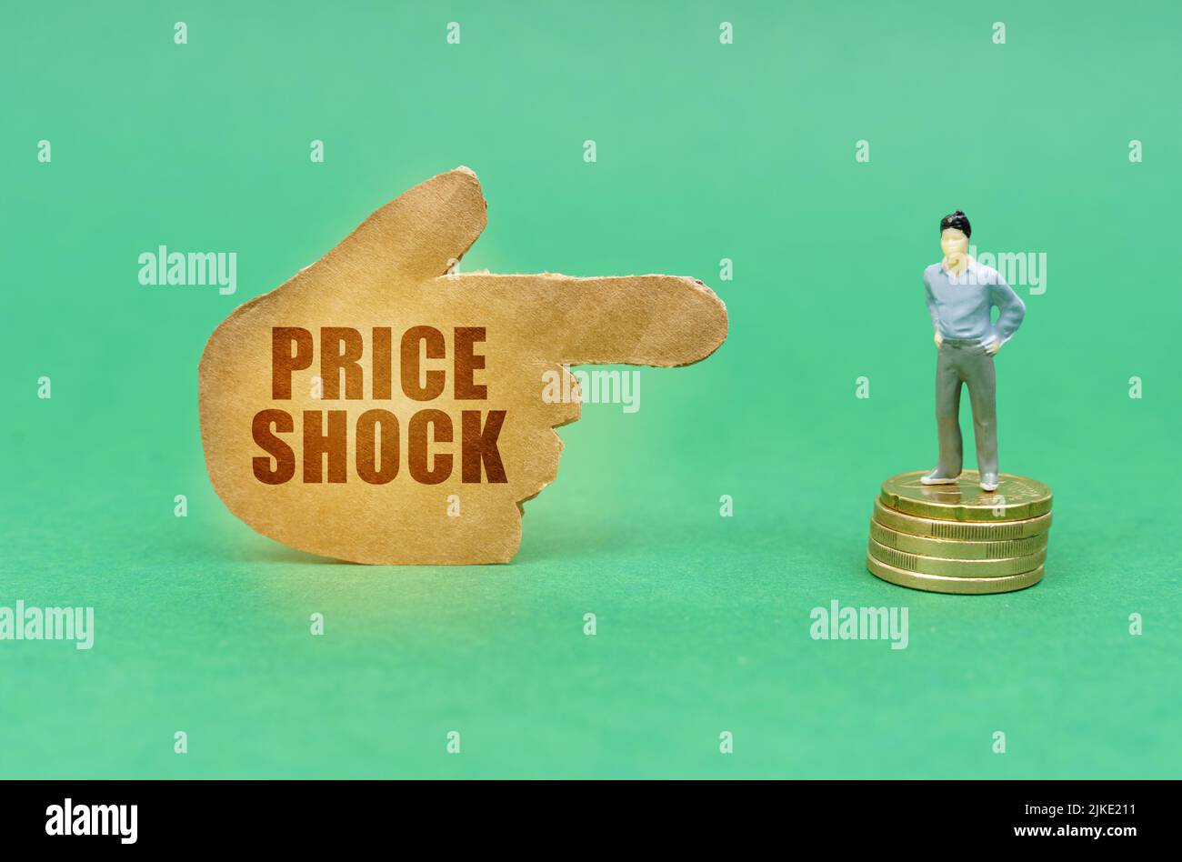 Business concept. On the green surface on the coins there is a figure of a man, a hand with the inscription points to him - price shock Stock Photo