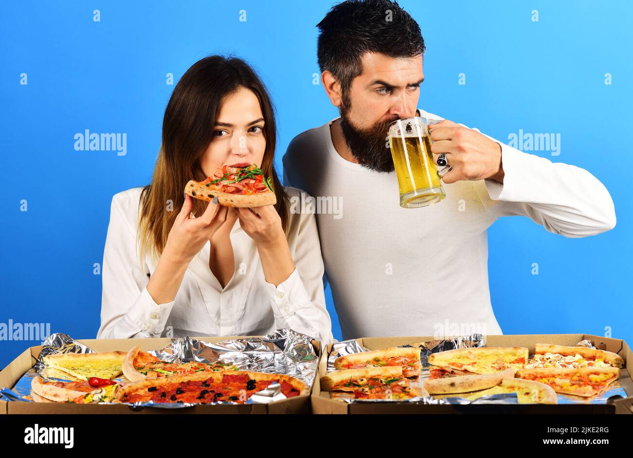 Pizza time. Beautiful young couple in casual clothes eating pizza and drinking beer together. Stock Photo