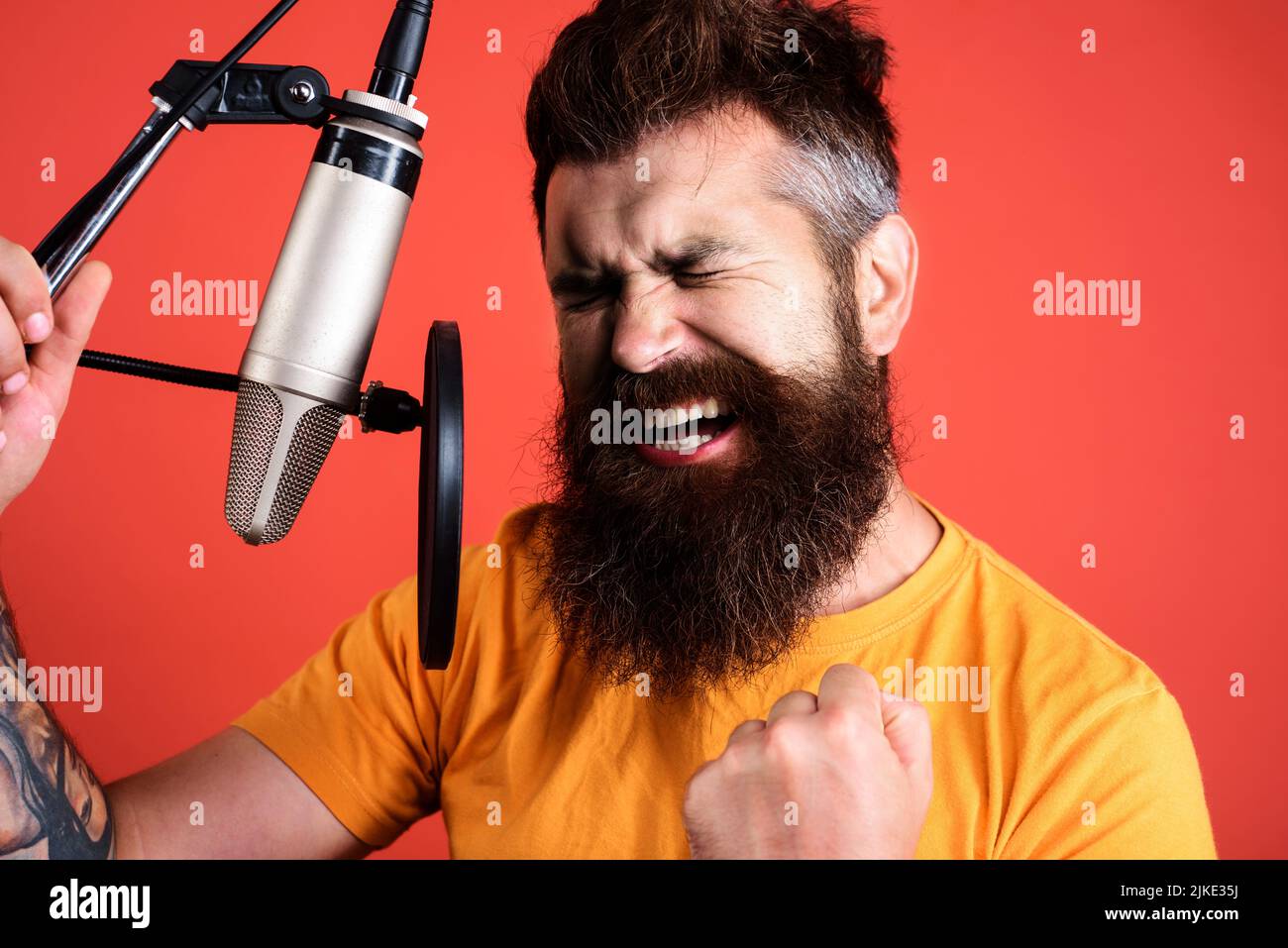 Emotional male singer singing in condenser microphone. Professional vocalist in studio. Music. Stock Photo