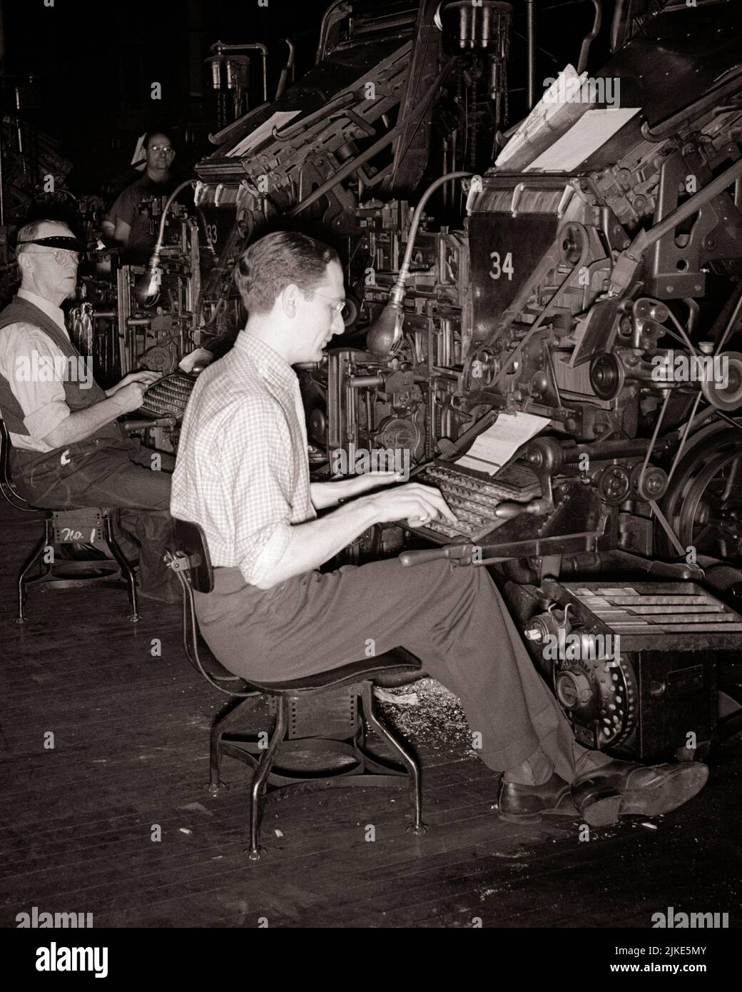 1930s TWO MEN AT KEYBOARDS OPERATING SIDE BY SIDE LINOTYPE MACHINES SETTING LINES OF TYPE FOR PRINTING PRESSES - i2049 HAR001 HARS CAREERS MACHINES PROGRESS INNOVATION LABOR EMPLOYMENT LINES OCCUPATIONS CONCEPTUAL TYPE INFRASTRUCTURE EMPLOYEE PRESSES KEYBOARDS YOUNG ADULT MAN BLACK AND WHITE CAUCASIAN ETHNICITY HAR001 LABORING OLD FASHIONED Stock Photo