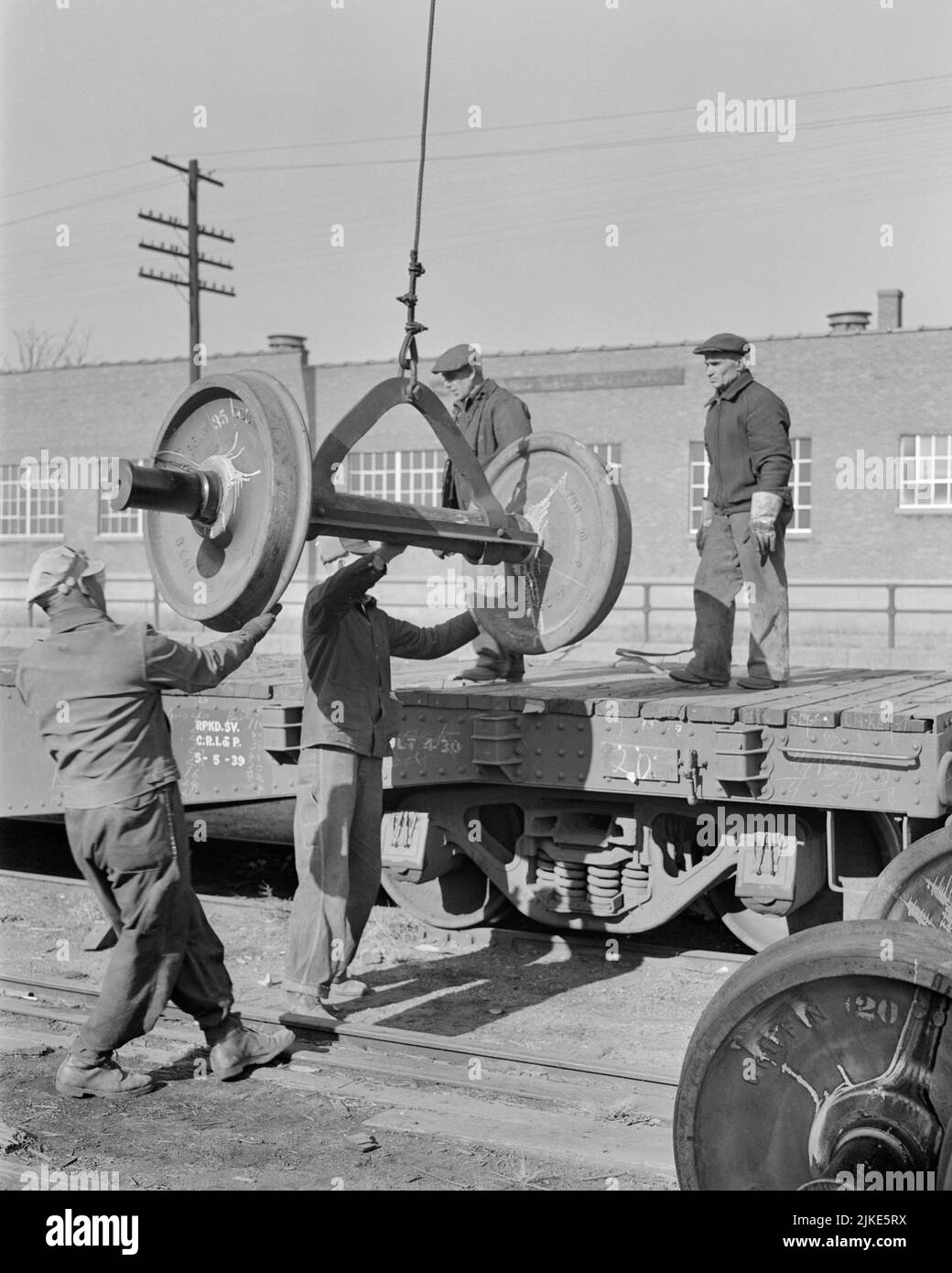 1930s MEN LOADING NEW RAILROAD CAR WHEELS ONTO FLATBED CAR PEORIA ILLINOIS USA - i254 HAR001 HARS NORTH AMERICA SERVICES LOADING NORTH AMERICAN RAIL SKILL OCCUPATION STRUCTURE SKILLS BUILD BASE CAREERS RECOVERY LABOR BETTER EMPLOYMENT OCCUPATIONS ONTO INFRASTRUCTURE PEORIA RAILROADS EMPLOYEE FACILITIES COOPERATION CORE ILLINOIS MID-ADULT MID-ADULT MAN SYSTEMS BLACK AND WHITE CAUCASIAN ETHNICITY ECONOMY FLATBED HAR001 IL LABORING OLD FASHIONED Stock Photo