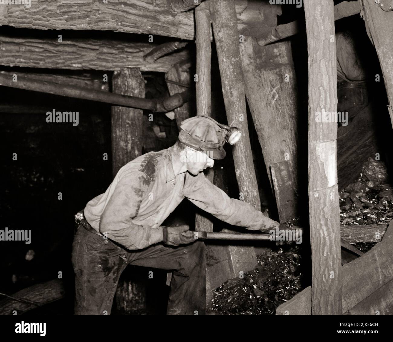 1940s MAN COAL MINER SHOVELING ANTHRACITE COAL IN PHILADELPHIA & READING COAL & IRON COMPANY MINE POTTSVILLE, PA USA - i829 HAR001 HARS MINER SHOVELING HIGH ANGLE HARD HAT MINERS PA LABOR WORLD WAR TWO WORLD WAR II EMPLOYMENT OCCUPATIONS COMPANY WORLD WAR 2 ANTHRACITE EMPLOYEE HEAD LAMP DEFENSE MID-ADULT MID-ADULT MAN BLACK AND WHITE CAUCASIAN ETHNICITY CIVILIAN HAR001 LABORING MINES OLD FASHIONED Stock Photo