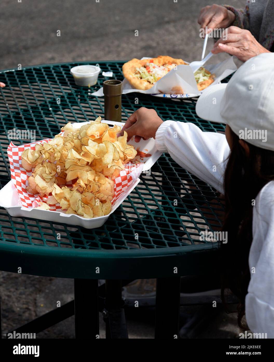 A family enjoys eating ribbon fries at an outdoor festival in Santa Fe, New Mexico. Stock Photo