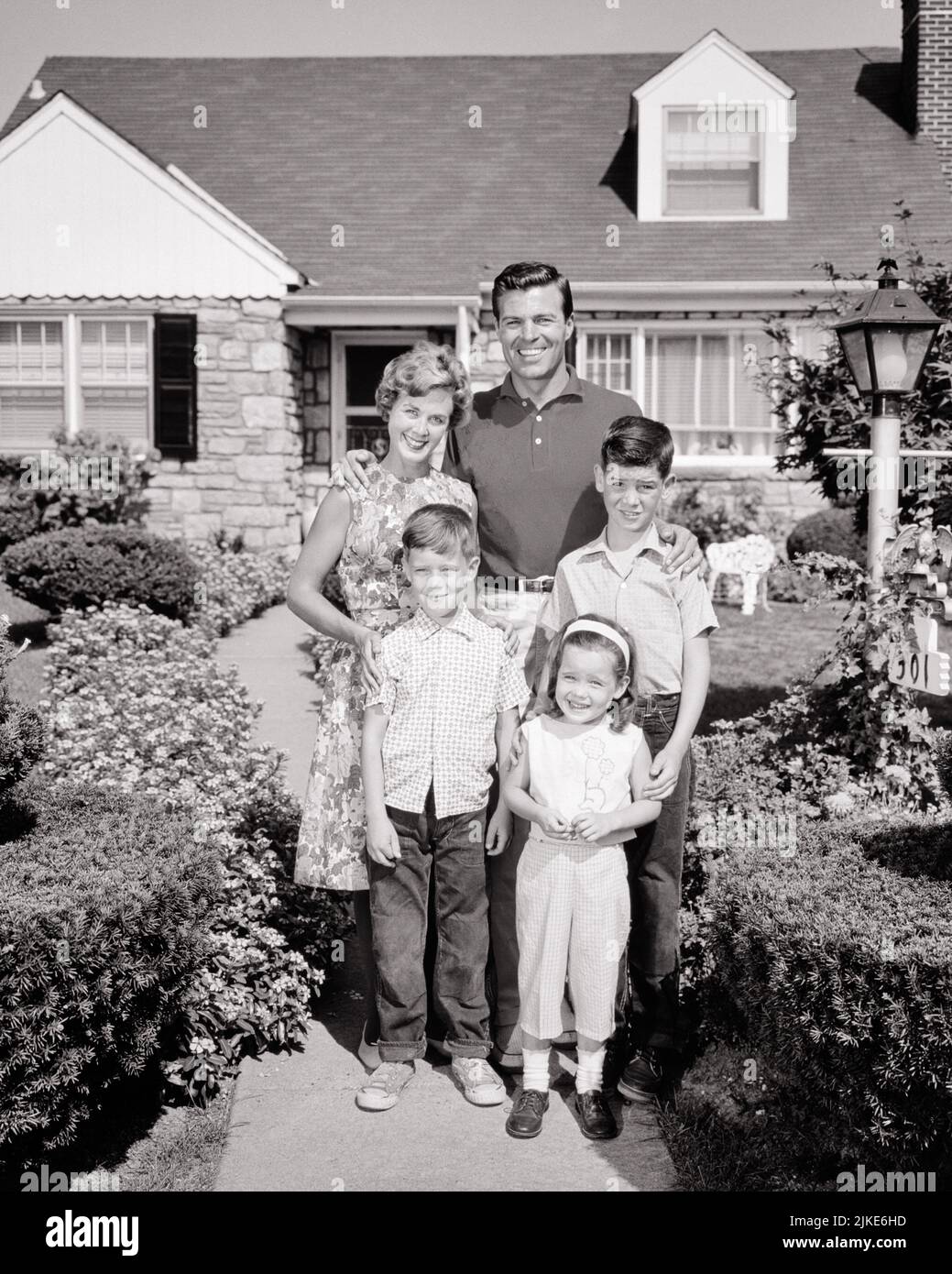 1960s PORTRAIT OF SMILING FAMILY OF FIVE STANDING IN FRONT OF THEIR SUBURBAN HOUSE MOTHER FATHER WITH TWO BOYS AND A GIRL - j11124 HAR001 HARS MOTHERS OLD TIME FUTURE NOSTALGIA BROTHER OLD FASHION SISTER 1 JUVENILE BALANCE STRONG SONS PLEASED FAMILIES JOY LIFESTYLE FIVE CELEBRATION FEMALES HOUSES MARRIED 5 BROTHERS SPOUSE HUSBANDS HOME LIFE COPY SPACE FULL-LENGTH LADIES DAUGHTERS PERSONS RESIDENTIAL CARING MALES BUILDINGS SIBLINGS SPIRITUALITY CONFIDENCE SISTERS FATHERS B&W PARTNER EYE CONTACT SUCCESS HAPPINESS CHEERFUL STRENGTH DADS PROGRESS PRIDE AUTHORITY HOMES SIBLING SMILES CONNECTION Stock Photo