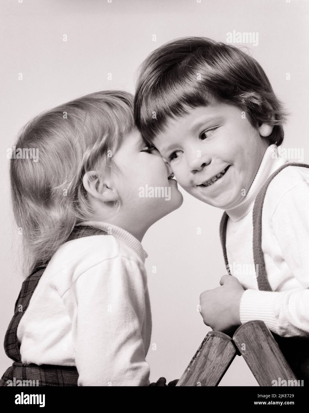 1960s TWO YOUNG GIRLS LITTLE SISTER EITHER WHISPERING IN OLDER ONE ON THE EAR OR KISSING HER ON CHEEK - j13192 HAR001 HARS SIBLINGS SISTERS B&W CHEERFUL SIBLING SMILES JOYFUL OR PERSONAL ATTACHMENT AFFECTION EMOTION JUVENILES PECK SMOOCH BABY GIRL BLACK AND WHITE CAUCASIAN ETHNICITY HAR001 OLD FASHIONED Stock Photo