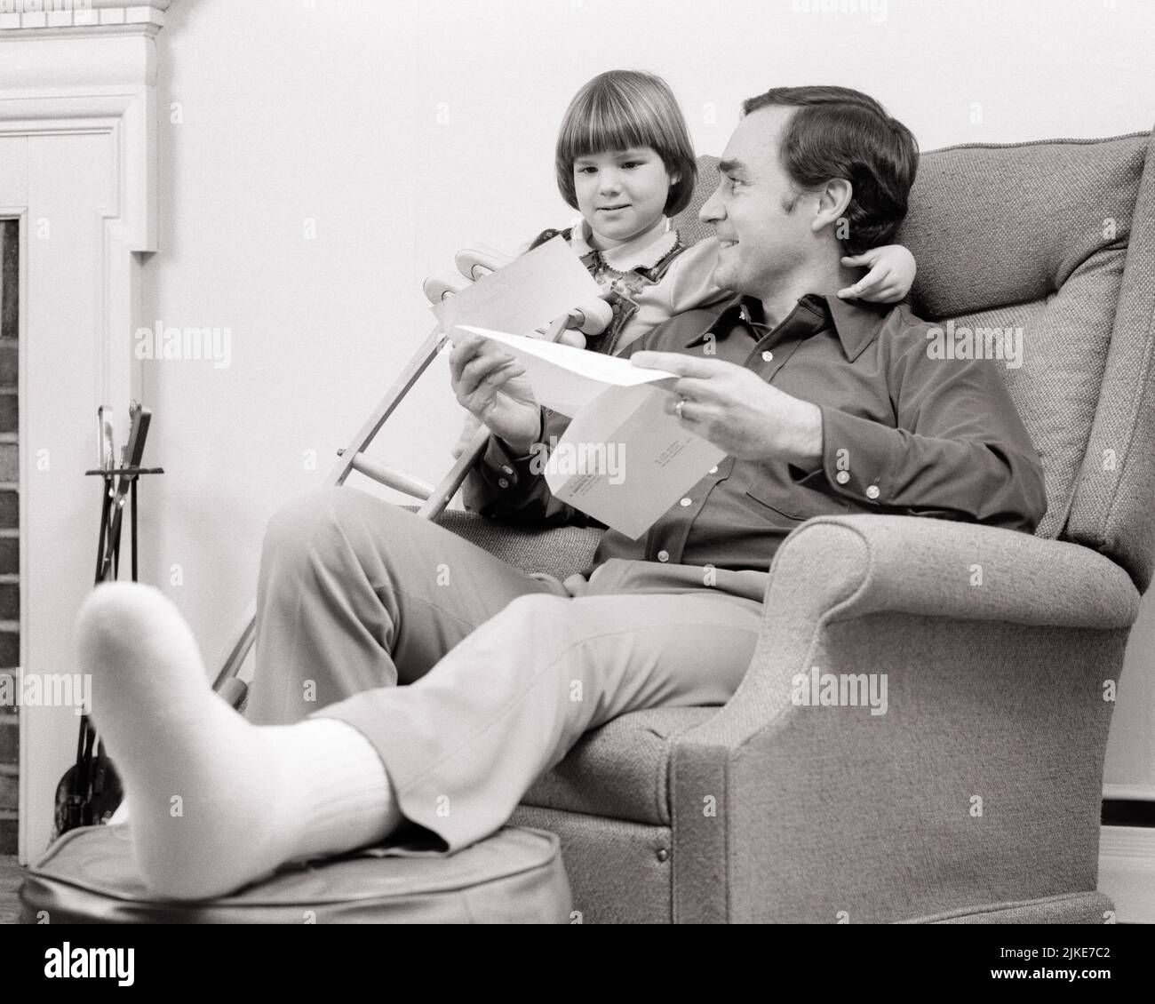 1970s FATHER SITTING INJURED FOOT ON OTTOMAN DAUGHTER HAS AN ARM AROUND DAD’S NECK HE HAS CRUTCH AND INSURANCE CHECK IN MAIL - j14016 HAR001 HARS JUVENILE INSURANCE COMMUNICATION NECK PLEASED JOY LIFESTYLE SATISFACTION FEMALES INJURED HOME LIFE COPY SPACE FRIENDSHIP HALF-LENGTH DAUGHTERS PERSONS MALES FATHERS B&W HAPPINESS CHEERFUL AND DADS LOW ANGLE PAYMENT SMILES CONNECTION CONCEPTUAL JOYFUL OTTOMAN HE CRUTCH JUVENILES MID-ADULT MID-ADULT MAN TOGETHERNESS BLACK AND WHITE CAUCASIAN ETHNICITY HAR001 OLD FASHIONED Stock Photo