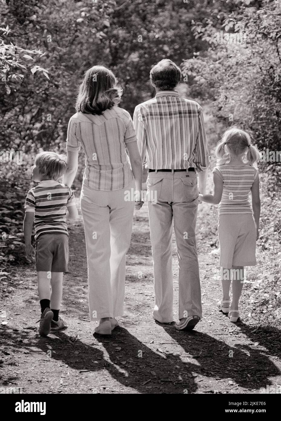 1970s FAMILY OF FOUR FROM BEHIND CASTING A SHADOW WALKING DOWN WOODED PATH HOLDING HANDS - j14169 HAR001 HARS DOWN HUSBAND DAD FOUR EXERCISING MOM SHADOW CLOTHING NOSTALGIC ACTIVE PAIR 4 MOTHERS OLD TIME NOSTALGIA OLD FASHION SISTER 1 FITNESS JUVENILE STYLE HEALTHY VACATION SONS FAMILIES JOY LIFESTYLE CELEBRATION FEMALES MARRIED RURAL SPOUSE HUSBANDS NATURE COPY SPACE FULL-LENGTH LADIES DAUGHTERS PERSONS CARING MALES SERENITY SISTERS FATHERS B&W PARTNER SUMMERTIME TIME OFF ACTIVITY PATH HAPPINESS PHYSICAL ADVENTURE STRENGTH TRIP GETAWAY DADS RECREATION HOLDING HANDS REAR VIEW HOLIDAYS Stock Photo