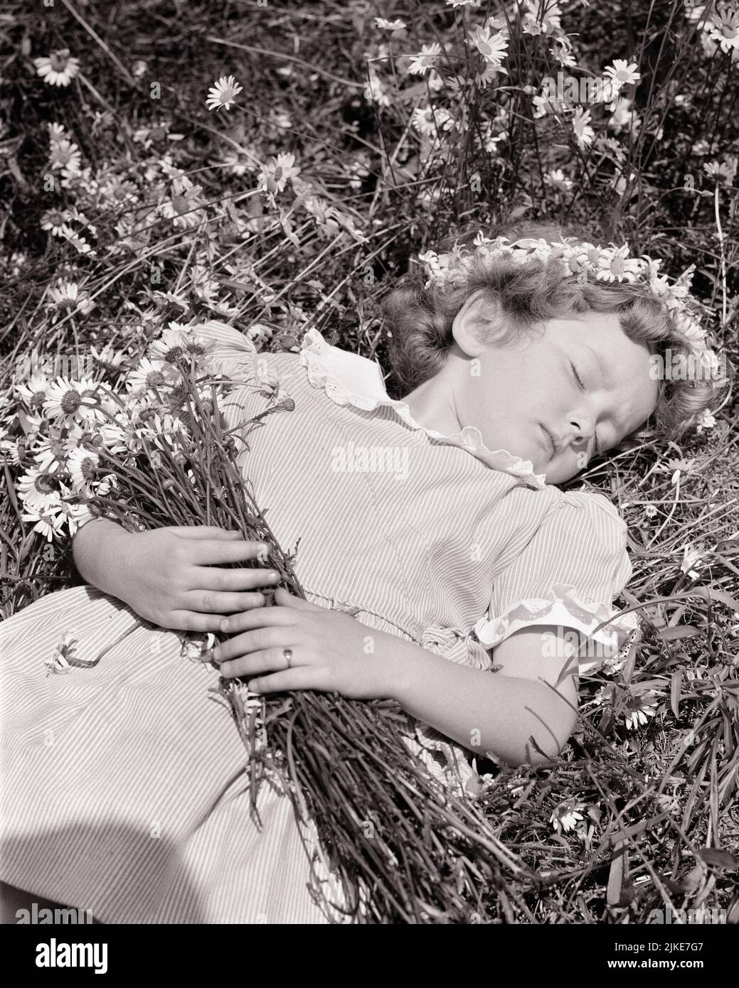 1940s 1950s LITTLE GIRL SLEEPING IN FIELD OF DAISIES WEARING A RING OF DAISY IN HER HAIR A CROWN AND A BOUQUET IN HER ARMS - j1524 HAR001 HARS RURAL NATURE COPY SPACE HALF-LENGTH STRIPES SERENITY B&W DAISY SUMMERTIME DAISIES DREAMS SLEEPY HIGH ANGLE ADVENTURE LEISURE AND DREAMING PEACEFUL CONCEPTUAL GROWTH IDYLLIC JUVENILES RELAXATION SEASON SLEEPING BEAUTY BLACK AND WHITE CAUCASIAN ETHNICITY HAR001 INNOCENCE INNOCENT OLD FASHIONED Stock Photo