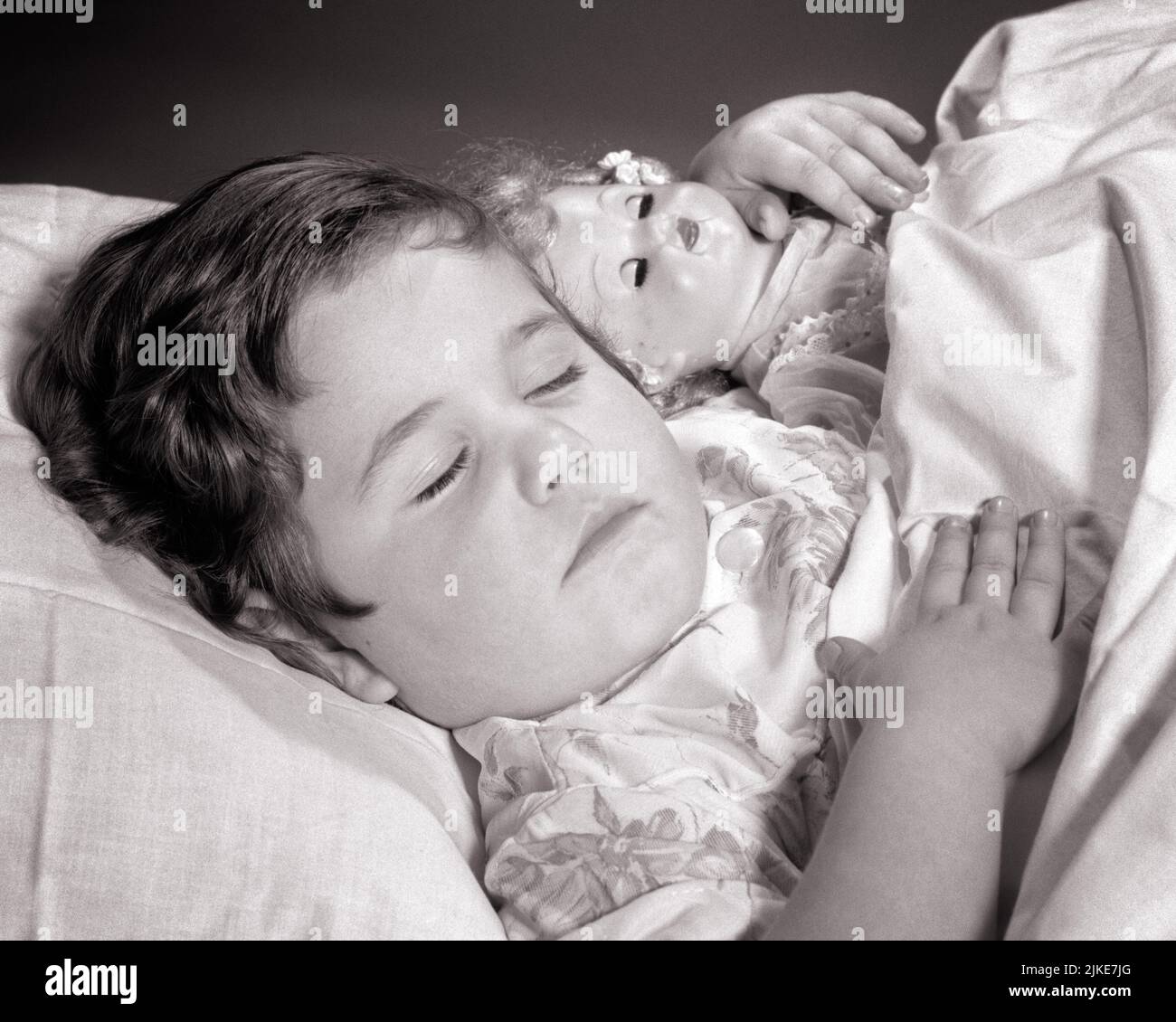 1960s BRUNETTE GIRL SLEEPING PEACEFULLY IN BED WITH ARM WRAPPED AROUND HOLDING HER DOLL - j1637 HAR001 HARS RELAXATION BLACK AND WHITE CAUCASIAN ETHNICITY HAR001 OLD FASHIONED Stock Photo