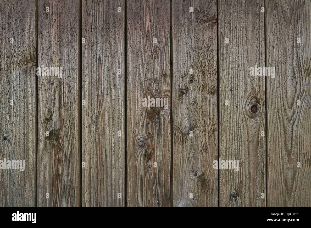 Old grey weathered outside wall of rustic barn covered with vertical worn wooden planks for texture or background. Stock Photo