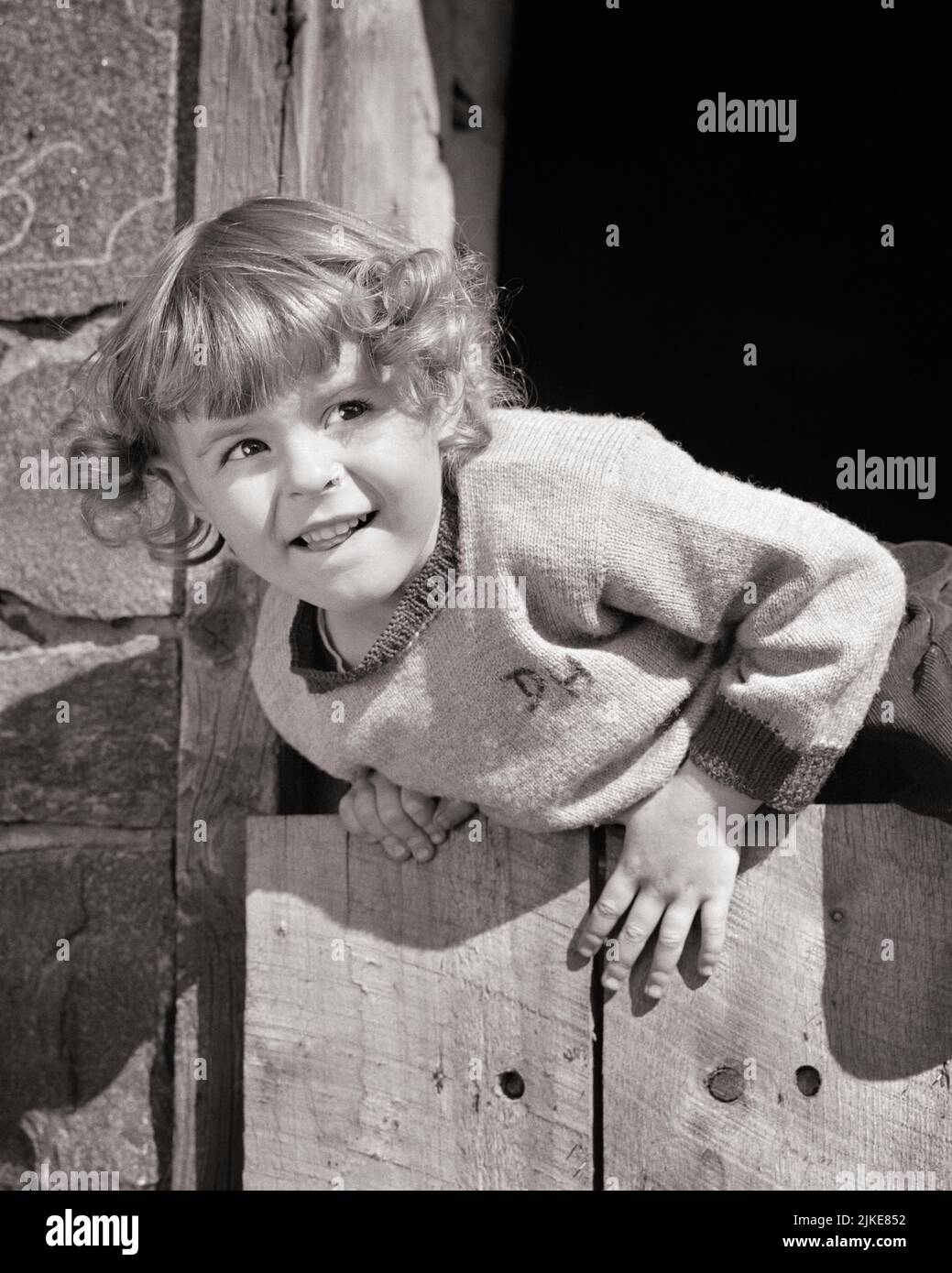 1940s 1950s CHARMING LITTLE GIRL DETERMINED TO CLIMB OVER A WOODEN FENCE - j497 HAR001 HARS EXPRESSIONS B&W TEMPTATION HEAD AND SHOULDERS ADVENTURE STRENGTH EFFORT TOMBOY ESCAPING CONCEPTUAL ATHLETES ESCAPE STRUGGLE DETERMINED JUVENILES BLACK AND WHITE CAUCASIAN ETHNICITY CHANCE HAR001 OLD FASHIONED Stock Photo