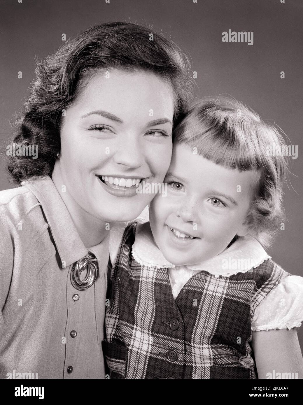 1950s Smiling Portrait Of Brunette Mother And Her Daughter Wearing A