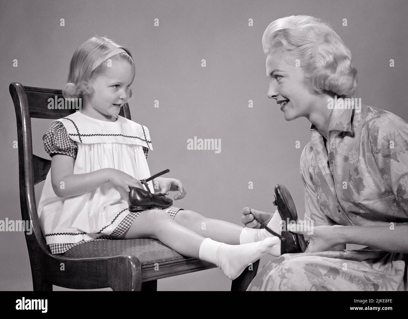 1960s BLONDE WOMAN MOTHER HELPING SMILING THREE YEAR OLD GIRL DAUGHTER PUT ON HER BLACK PATENT LEATHER MARY JANE SHOES - j8317 HAR001 HARS URBAN HER MOTHERS OLD TIME NOSTALGIA OLD FASHION 1 JUVENILE STYLE COMMUNICATION BLOND TEAMWORK STRONG PLEASED FAMILIES JOY LIFESTYLE PARENTING CELEBRATION FEMALES HOME LIFE FULL-LENGTH HALF-LENGTH LADIES DAUGHTERS PERSONS CARING CONFIDENCE MARY B&W PATENT WIDE ANGLE PUT HAPPINESS CHEERFUL EXCITEMENT MARY JANE PRIDE ON SMILES CONNECTION CONCEPTUAL JOYFUL STYLISH PERSONAL ATTACHMENT AFFECTION COOPERATION EMOTION GROWTH JANE JUVENILES MID-ADULT MID-ADULT WOMAN Stock Photo