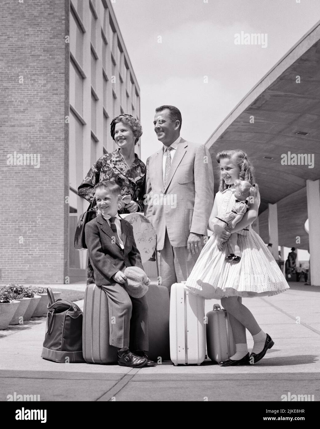 1950s FAMILY OF FOUR ON VACATION TRIP ARRIVED DRESSED FOR TRAVEL CARRYING LUGGAGE MOTHER FATHER WITH TWO KIDS WAITING FOR TAXI  - j9105 HAR001 HARS TRAVEL MOM LUGGAGE NOSTALGIC PAIR 4 BEAUTY URBAN MOTHERS OLD TIME BUSY NOSTALGIA BROTHER OLD FASHION SISTER 1 JUVENILE SECURITY BALANCE TEAMWORK VACATION STRONG TAXI SUITCASES SONS FAMILIES JOY LIFESTYLE CELEBRATION FEMALES MARRIED BROTHERS SPOUSE HUSBANDS LUXURY COPY SPACE FULL-LENGTH LADIES DAUGHTERS PERSONS CARING MALES ENTERTAINMENT SIBLINGS CONFIDENCE SISTERS TRANSPORTATION FATHERS B&W PARTNER TIME OFF SUIT AND TIE HAPPINESS ADVENTURE LEISURE Stock Photo