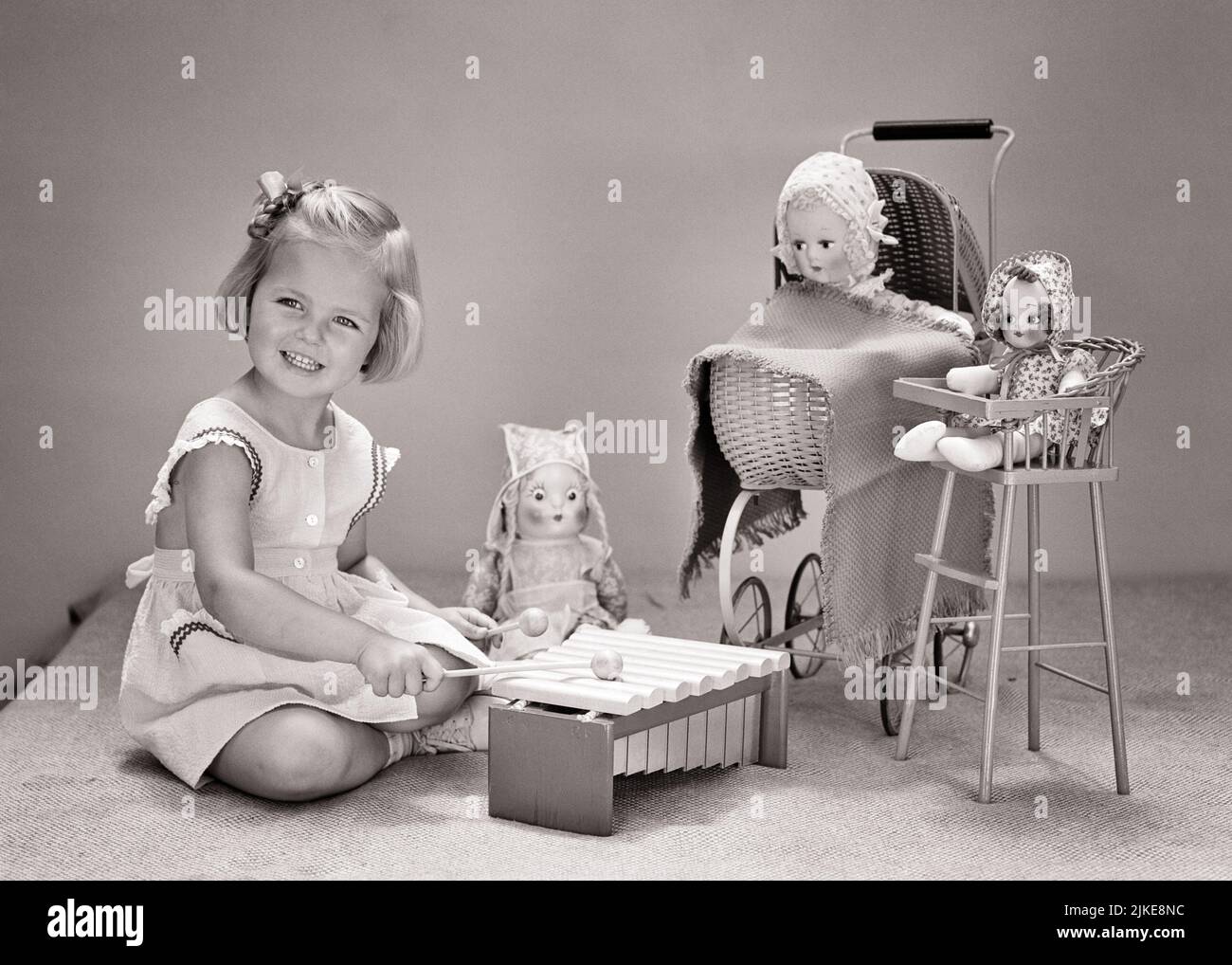 1940s SMILING BLONDE GIRL PLAYING TOY XYLAPHONE WITH WOODEN MALLETS WITH HER DOLLS FOR AN AUDIENCE - j9298 HAR001 HARS SOUND SATISFACTION MUSICIAN FEMALES STUDIO SHOT HEALTHINESS HOME LIFE COPY SPACE HALF-LENGTH INSPIRATION CONFIDENCE B&W PERFORMING ARTS HAPPINESS CHEERFUL HIGH ANGLE PRIDE SMILES MUSICAL INSTRUMENT CONCEPTUAL IMAGINATION JOYFUL MALLETS CREATIVITY GROWTH HIGH CHAIR JUVENILES BLACK AND WHITE CAUCASIAN ETHNICITY HAR001 OLD FASHIONED Stock Photo