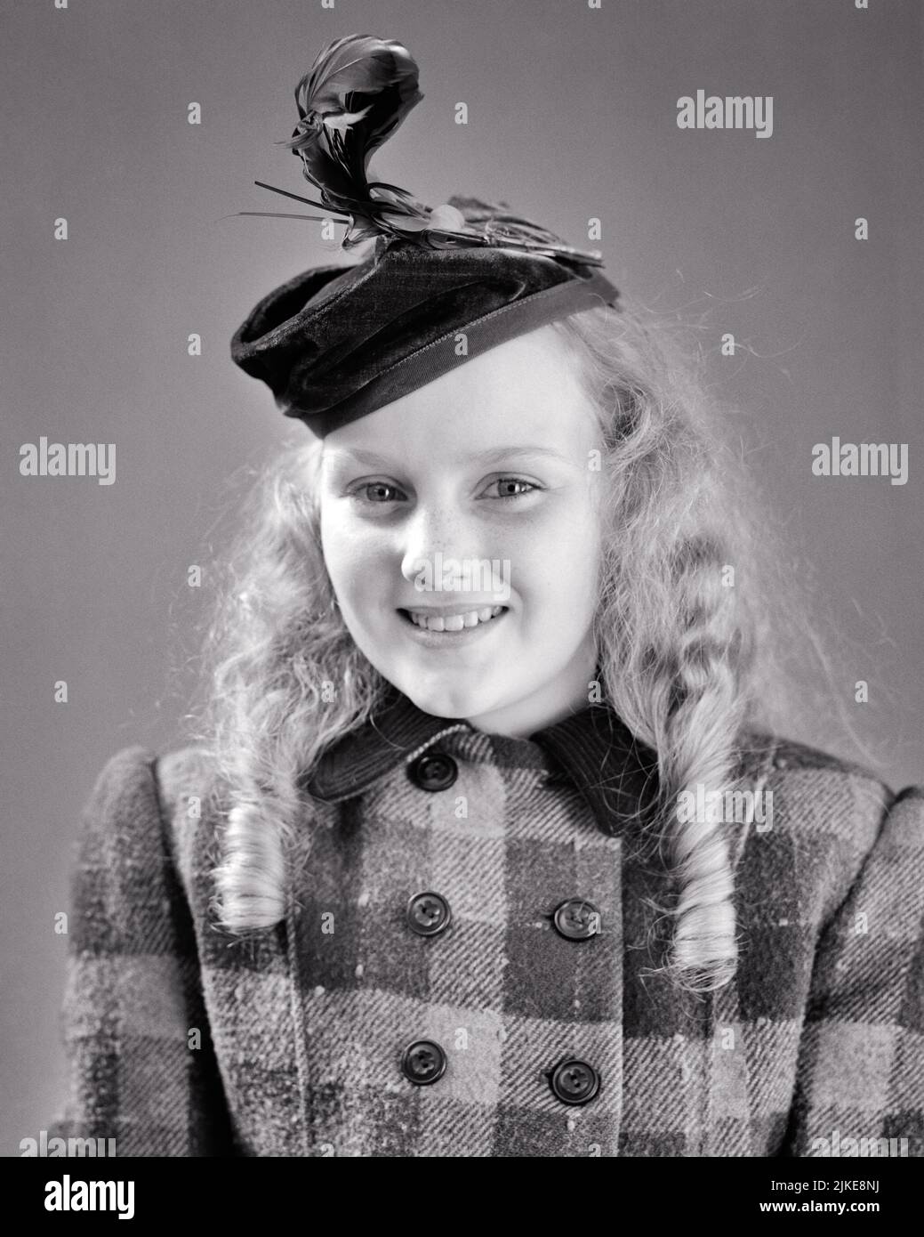 1940s SMILING YOUNG BLONDE GIRL WEARING SILLY HAT WITH FEATHER LONG HAIR IN BALONEY CURLS PLAID DOUBLE BREASTED WOOLEN COAT - j9203 HAR001 HARS STUDIO SHOT HEALTHINESS COPY SPACE HALF-LENGTH PLAID FRECKLES CONFIDENCE B&W EYE CONTACT HAPPINESS CHEERFUL STYLES CURLS PRIDE SMILES JOYFUL STYLISH WOOLEN BALONEY BREASTED FASHIONS GROWTH JUVENILES PRE-TEEN PRE-TEEN GIRL BLACK AND WHITE CAUCASIAN ETHNICITY HAR001 OLD FASHIONED Stock Photo