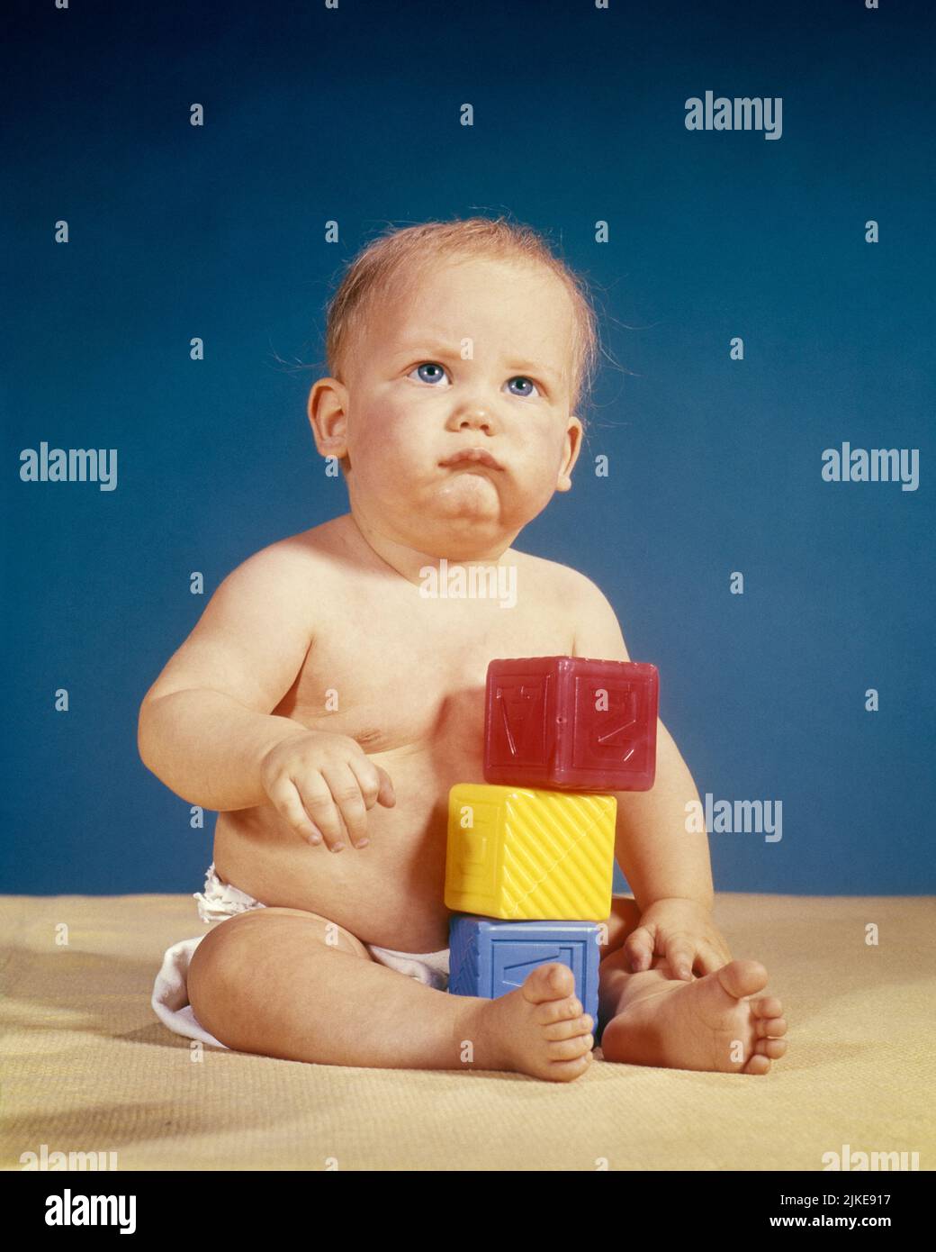 1950s UNHAPPY BABY BOY PLAYING WITH PLASTIC BUILDING BLOCKS LOOKING UP WITH GRUMPY FACIAL EXPRESSION - kb6071 HAR001 HARS COPY SPACE FULL-LENGTH MALES DIAPER EXPRESSIONS TROUBLED CONCERNED SADNESS EYE CONTACT STACKING RECREATION UP MOOD CONCEPTUAL GLUM BABY BOY SOURPUSS DISGRUNTLED JUVENILES MISERABLE CAUCASIAN ETHNICITY HAR001 OLD FASHIONED Stock Photo