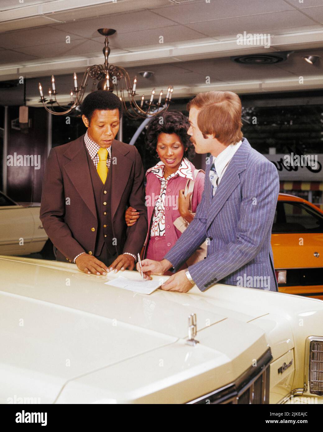 1970s AFRICAN AMERICAN COUPLE TALKING WITH CAUCASIAN NEW CAR SALESMAN IN AUTOMOBILE SHOWROOM - km4935 HAR001 HARS 1 STYLE WELCOME DIVERSE COMMUNICATION VEHICLE YOUNG ADULT TEAMWORK INFORMATION DIFFERENT SHOWROOM LIFESTYLE FEMALES MARRIED SPOUSE HUSBANDS LUXURY COPY SPACE FRIENDSHIP HALF-LENGTH LADIES PERSONS AUTOMOBILE MALES TRANSPORTATION VEST PARTNER FREEDOM GOALS SUIT AND TIE SELLING ADVENTURE STYLES CUSTOMER SERVICE AFRICAN-AMERICANS AFRICAN-AMERICAN AUTOS EXCITEMENT BLACK ETHNICITY OCCUPATIONS THREE PIECE SUIT CONCEPTUAL AUTOMOBILES INSPECTING STYLISH VARIOUS VEHICLES NEW CAR VARIED Stock Photo