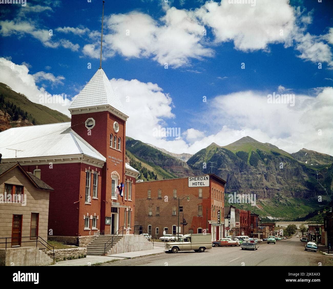 1960s THE MAIN STREET COLORADO AVENUE WITH SHERIDAN HOTEL AND SAN MIGUEL COUNTY COURT HOUSE TELLURIDE CO USA - kr10810 HAR001 HARS AND AUTOS EXTERIOR REAL ESTATE STRUCTURES AUTOMOBILES VEHICLES EDIFICE SMALL TOWN TELLURIDE ROCKY MOUNTAINS SAN JUAN MOUNTAINS SAN MIGUEL COUNTY COLORADO HAR001 MAIN STREET OLD FASHIONED SHERIDAN Stock Photo