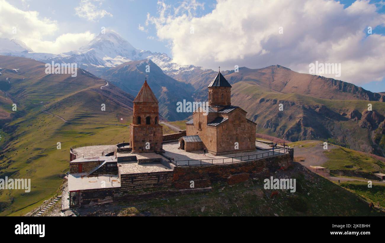 amazing aerial view of Gergeti Trinity Church surrounded by the Caucasus mountains in the sunny weather, Kazbegi, Georgia. High quality photo Stock Photo