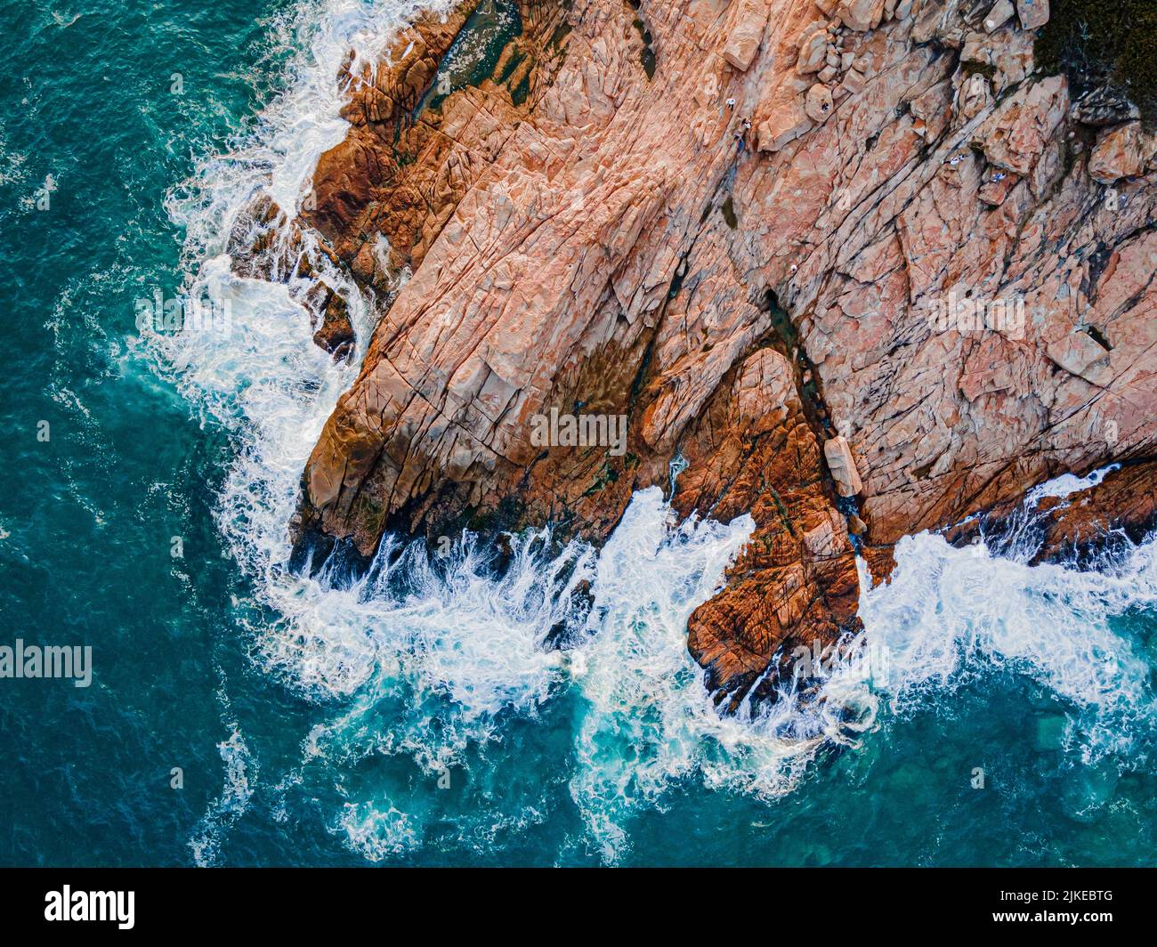 An aerial top view of sea waves splashing against brown cliffs Stock ...