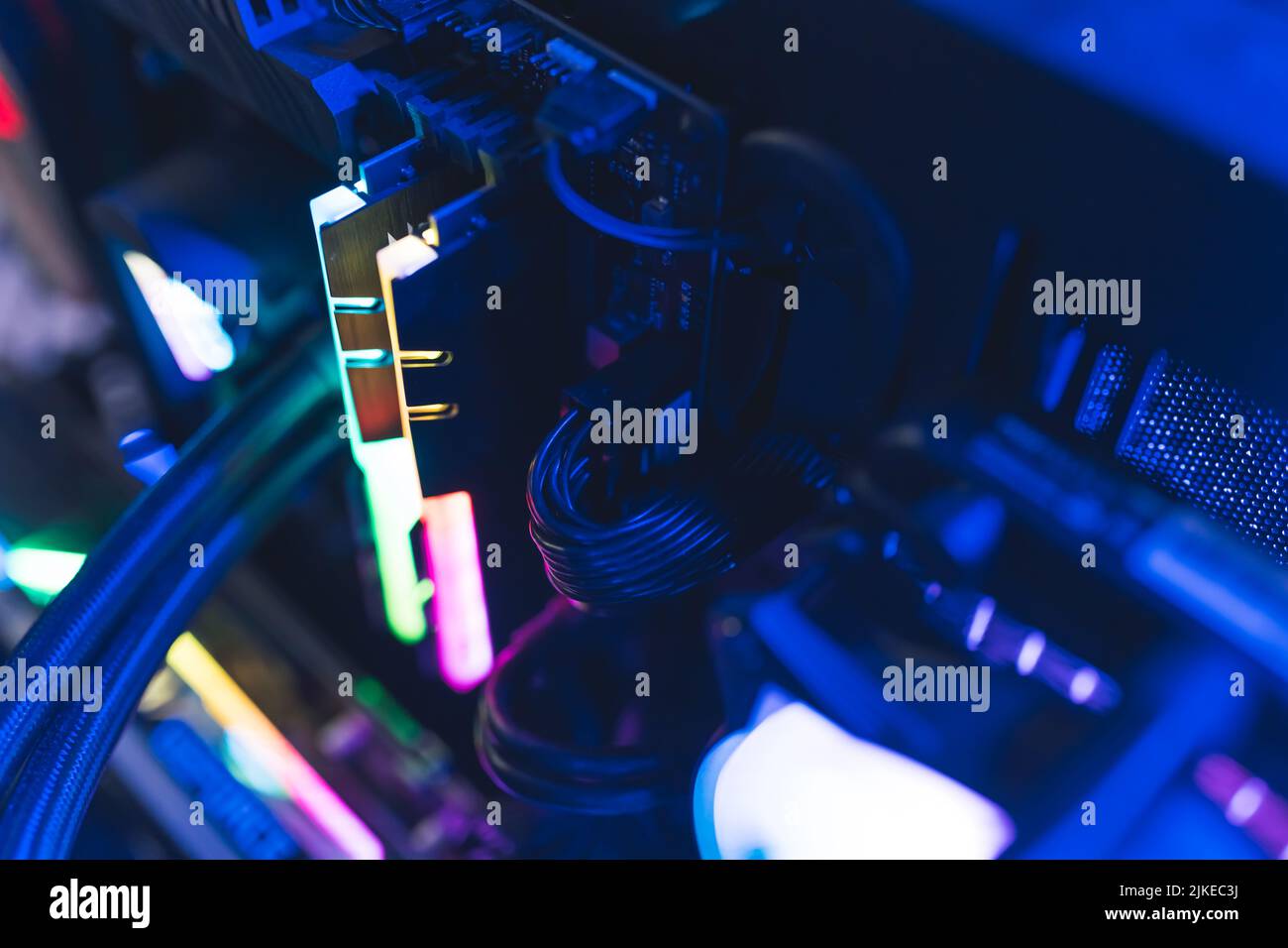 Professional gaming computer setup close-up. Glowing parts in rainbow colors and cables. Dark blue lighting. High quality photo Stock Photo