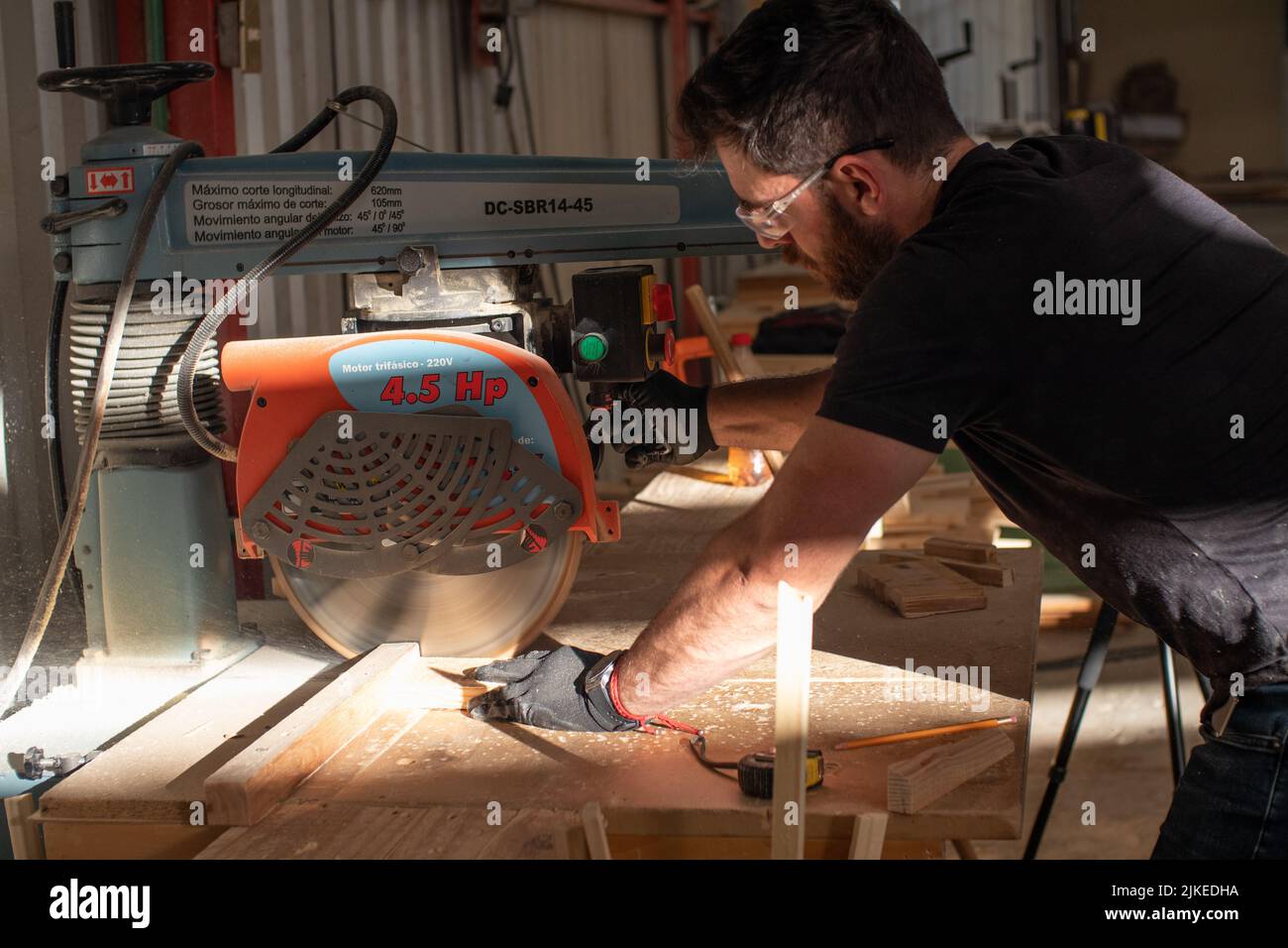 young carpenter working on a circular saw machine cutting a wooden