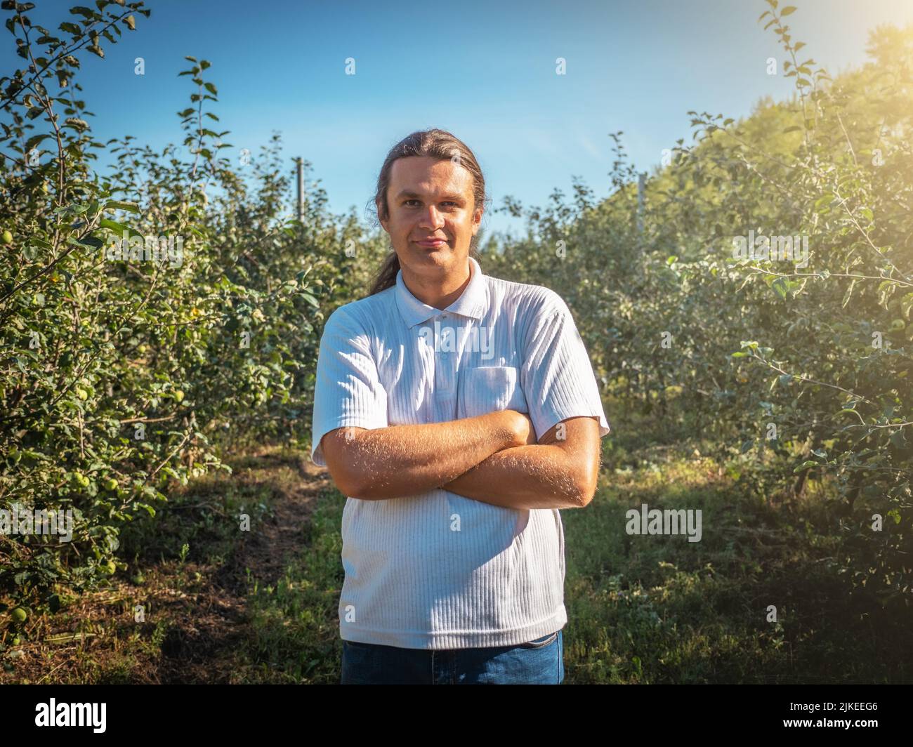Portrait of happy farmer among rows of trees in garden after harvest. Stock Photo