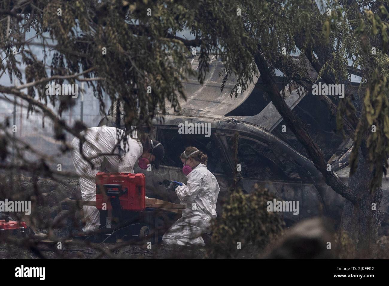 Forensic anthropologists look for human remains in a damaged vehicle as the McKinney Fire burns near Yreka, California, U.S.,  August 1, 2022. REUTERS/Carlos Barria Stock Photo