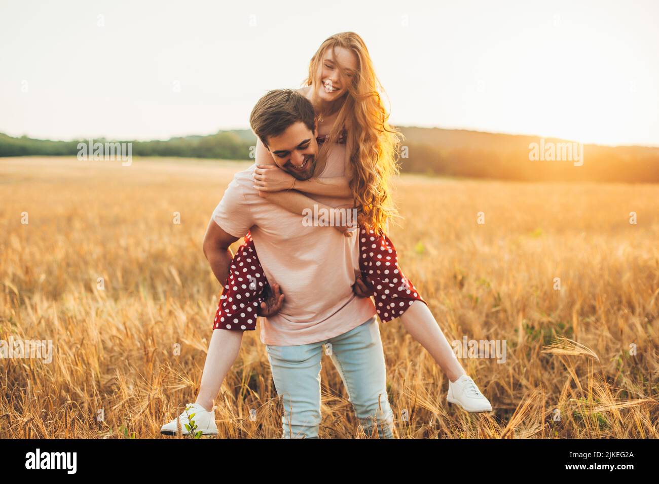 Caucasian woman enjoying piggy back ride with her boyfriend, enjoy a relaxing day in the countryside in a colorful yellow rapeseed field. Activity Stock Photo