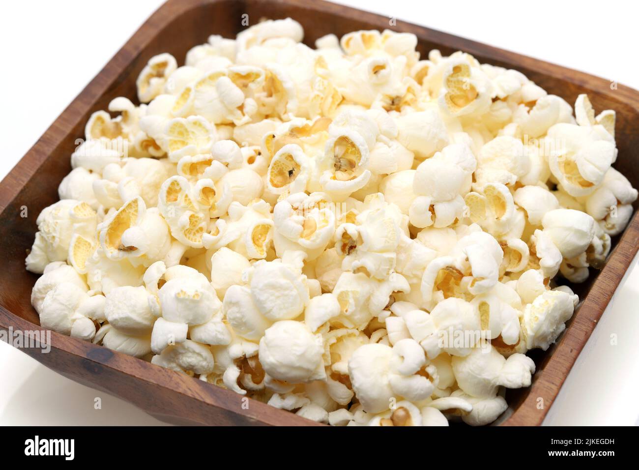 Popcorn in wooden bowl on white background, Side view, Close up Stock Photo