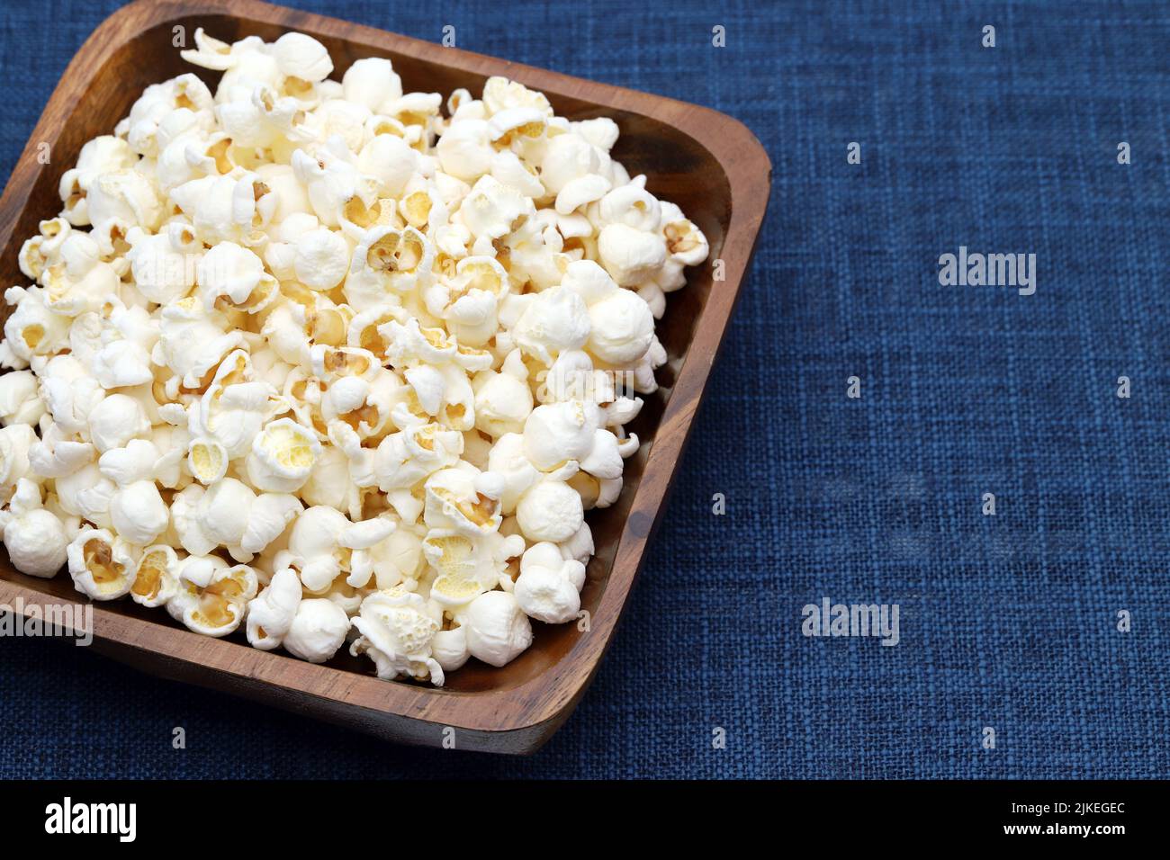 Popcorn in wooden bowl on table, Side view, Close up Stock Photo
