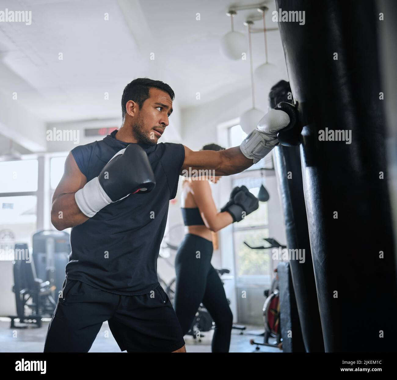 Active, fit and serious man boxing, sweating and doing a cardio workout at the gym. One sporty, sweaty and determined male athlete looking tired while Stock Photo