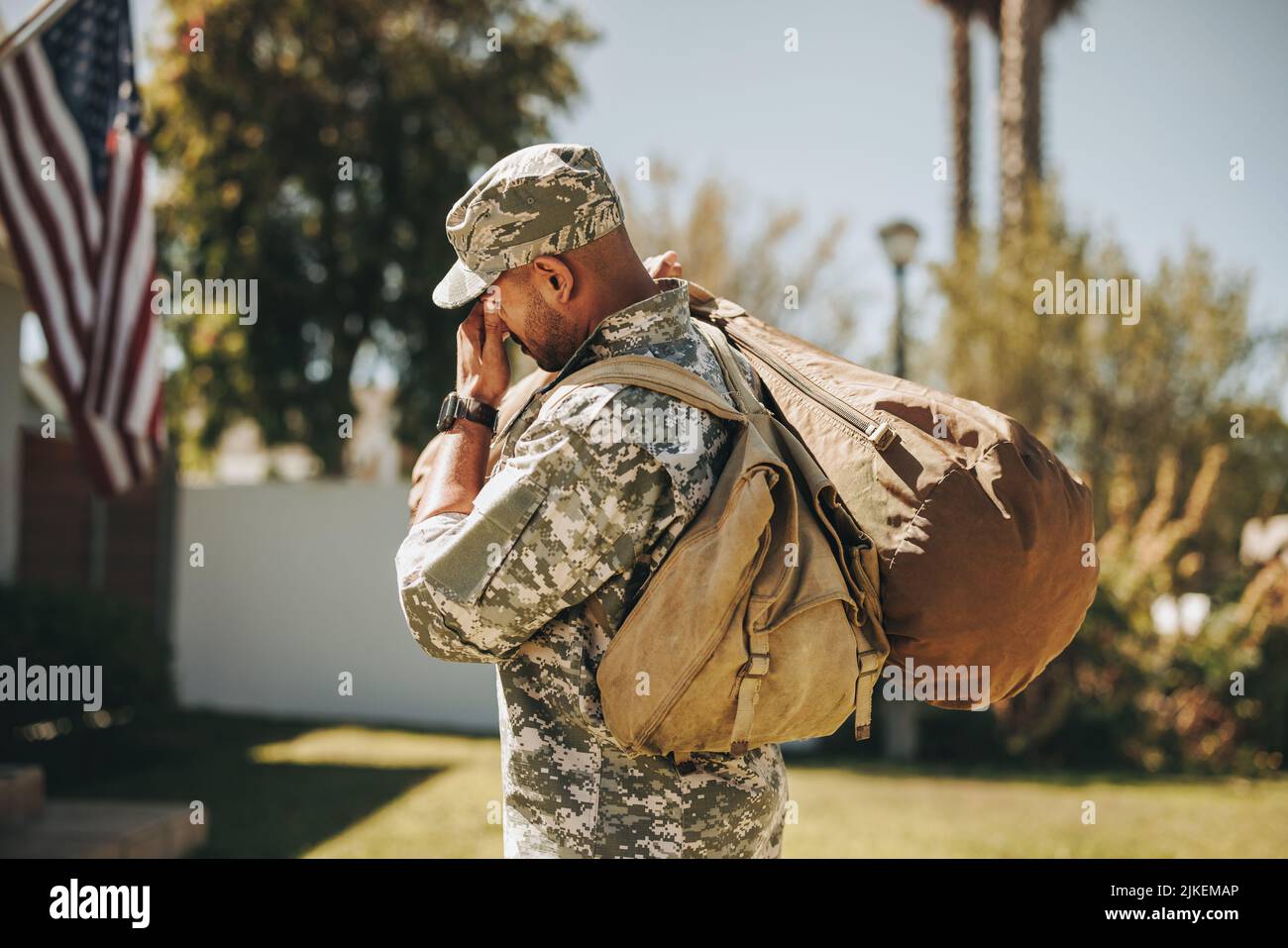 Emotional soldier walking towards his house with his luggage. American serviceman coming back home after serving in the army. Stock Photo