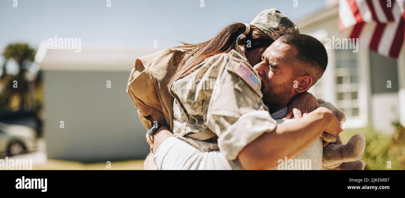 Female soldier embracing her husband after returning home from the army. American servicewoman having an emotional reunion with her husband after serv Stock Photo
