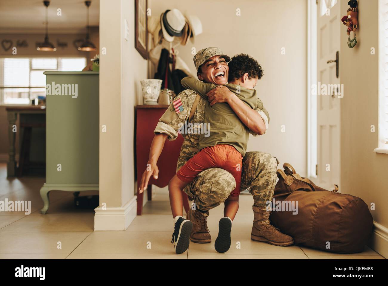 Excited military mom embracing her son after returning home from the army. Cheerful female soldier having a joyful reunion with her young child after Stock Photo