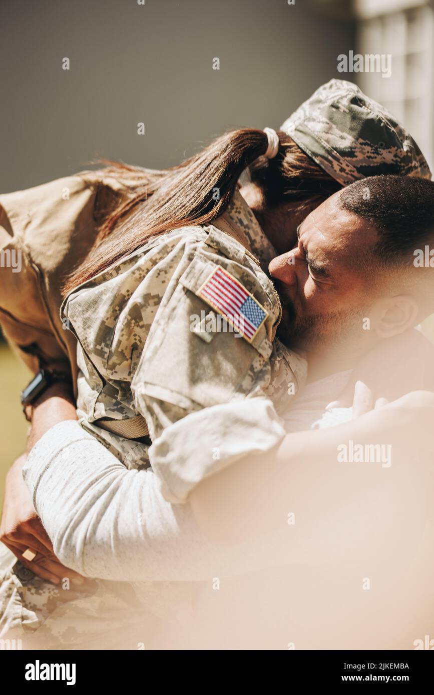 Patriotic female soldier embracing her husband after returning home from the army. American servicewoman having an emotional reunion with her husband Stock Photo